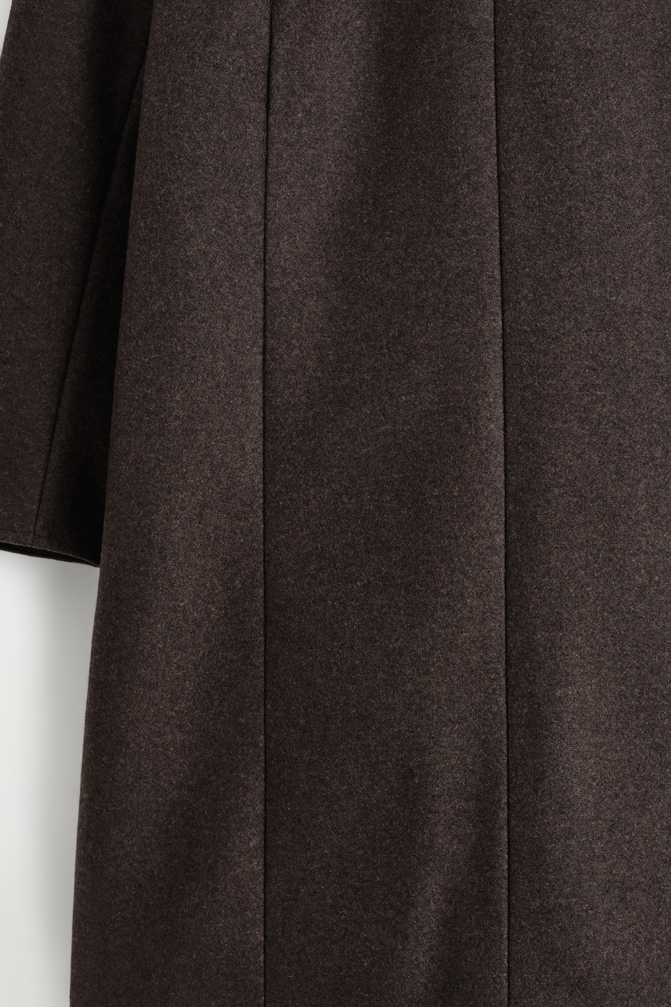 Ver imagen más grande: Un vestido mini de color marrón oscuro está mostrando un primer plano de su tejido texturizado, con costuras verticales que moldean el panel de la prenda.