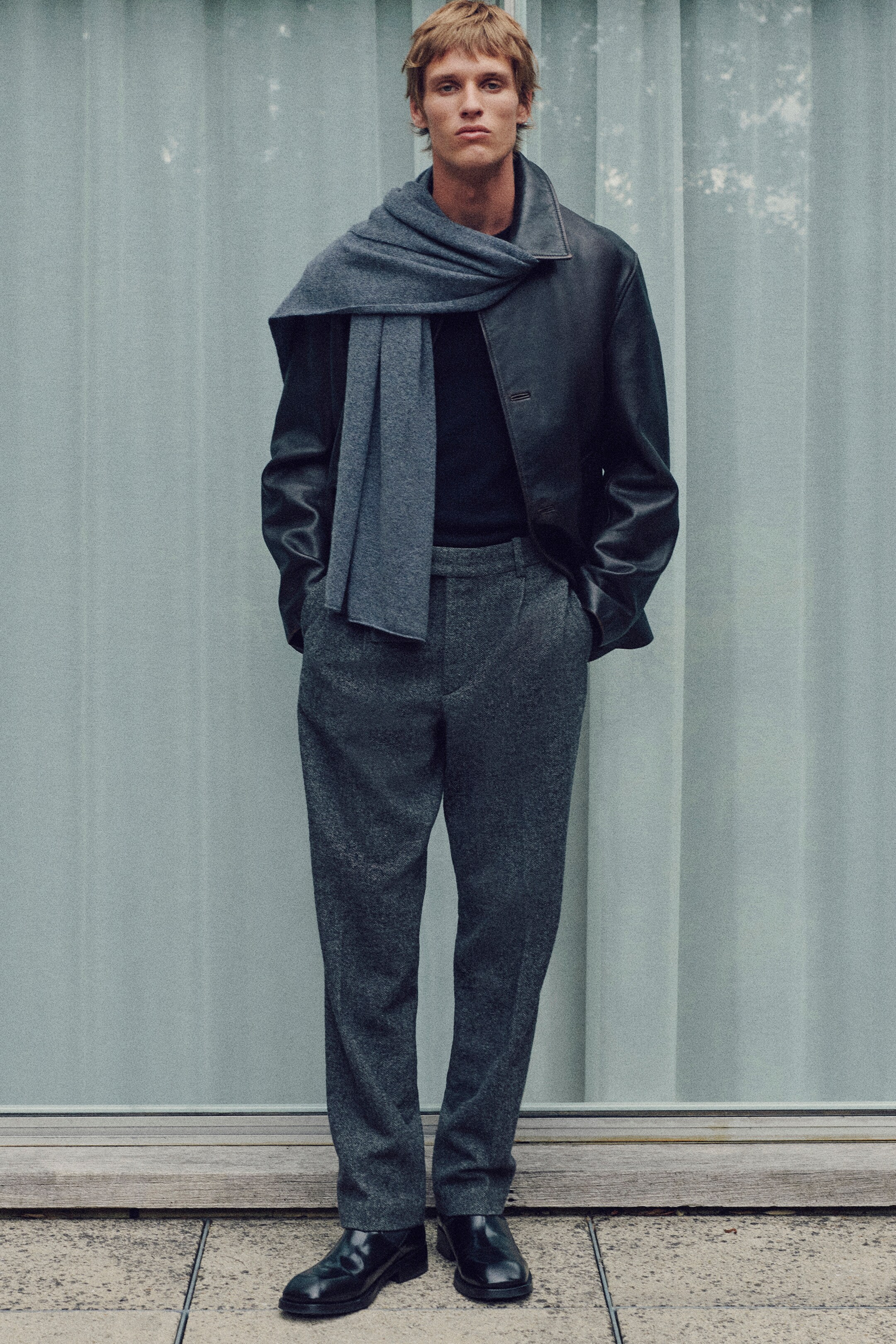 View larger image: A grey enveloping scarf is draped around the model's neck and right shoulder, with one end hanging down the front. The model is also wearing black leather shoes with rounded toes and a low heel.