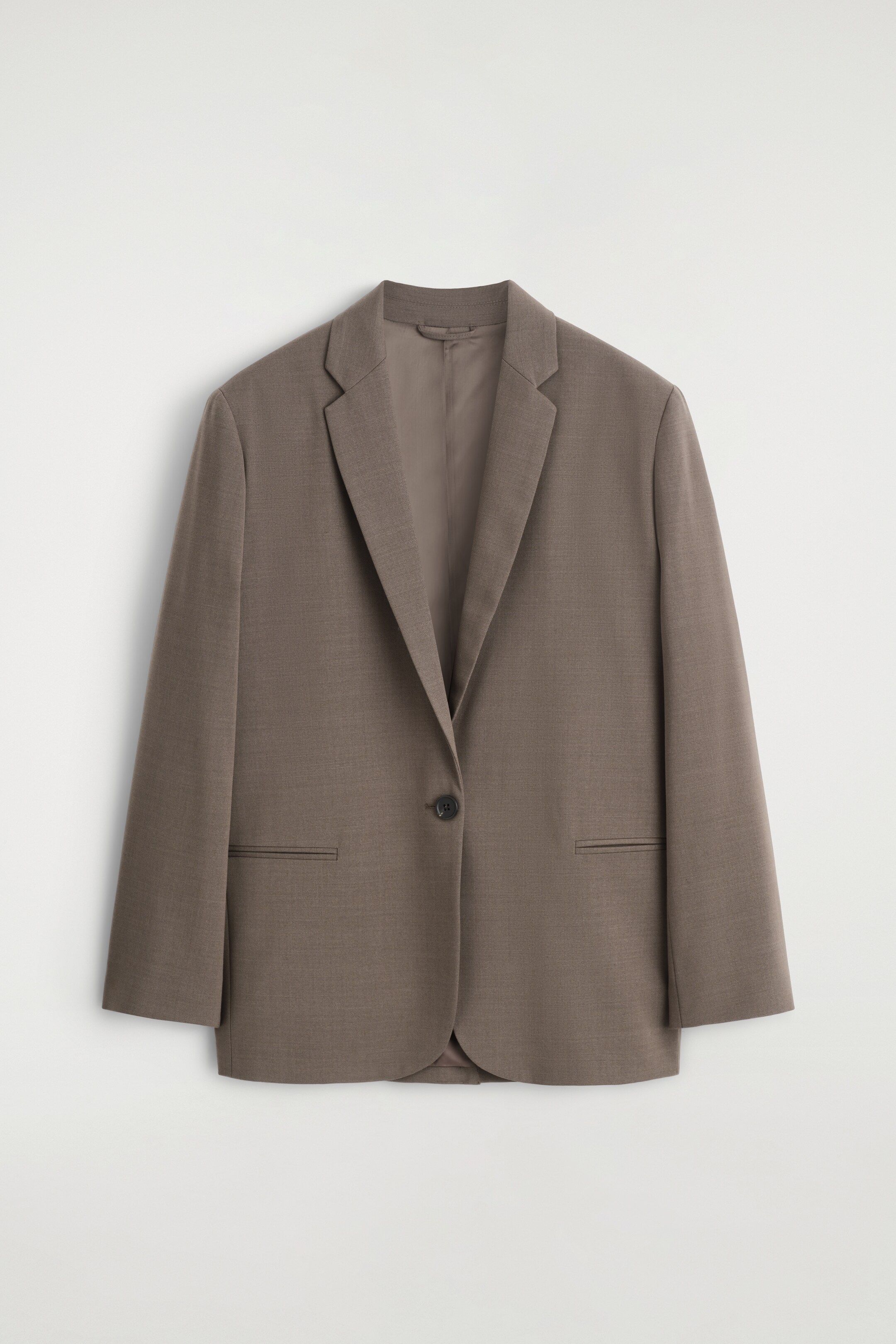Ver imagem maior: Um blazer taupe de abotoamento simples está a ser apresentado de FRENTE, com uma silhueta descontraída. Apresenta lapelas de entalhe, um único botão escuro e dois bolsos horizontais de jato, tudo num tecido suave e finamente texturizado.