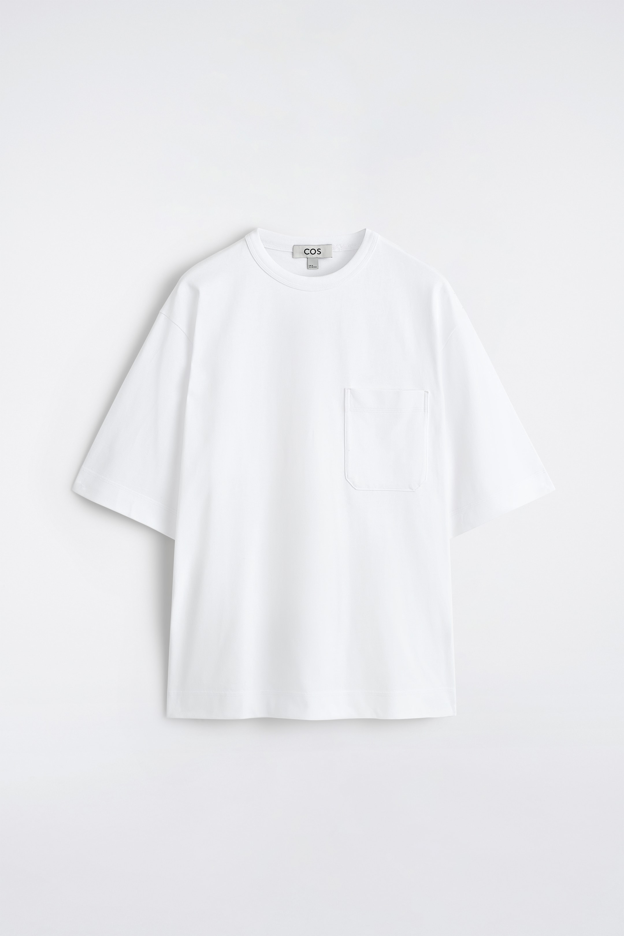 Visualizza immagine più grande: Una T-shirt bianca oversize presenta il suo fronte, caratterizzata da un girocollo, maniche corte e larghe, e una tasca applicata sul petto sinistro.