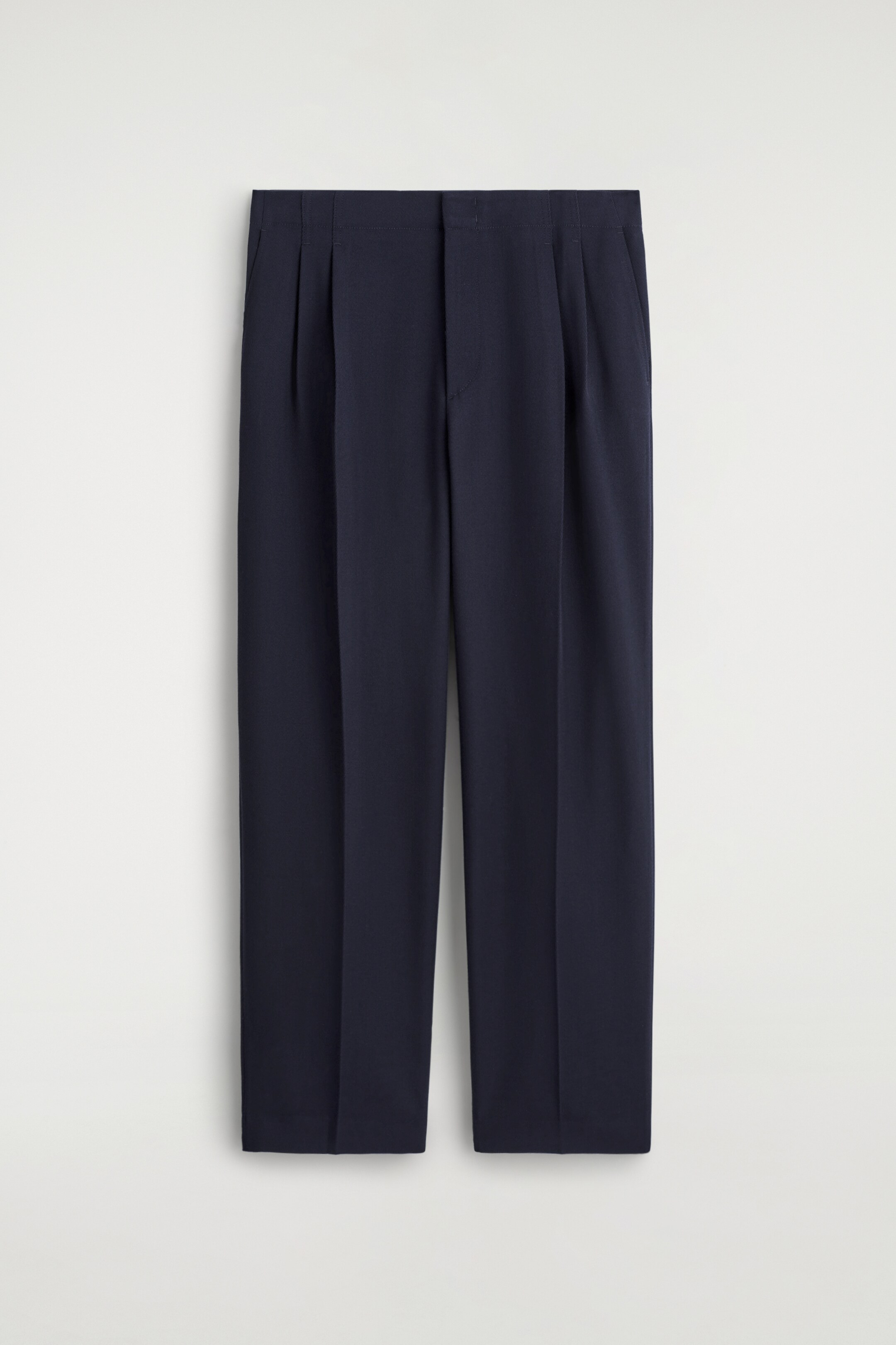 View larger image: Navy trousers are presented facing FRONT, showing a relaxed, straight-leg fit. They are featuring a flat front waistband with a double row of pleats on each side and subtle side pockets.