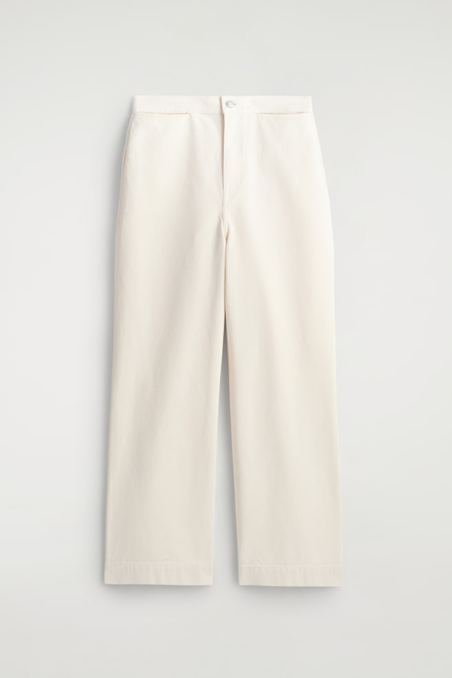 Ecru cotton wide-leg trousers are displayed flat, facing front. They feature a high-rise waist with a button and zip fastening, front pockets, and wide legs with cropped hems. - 1