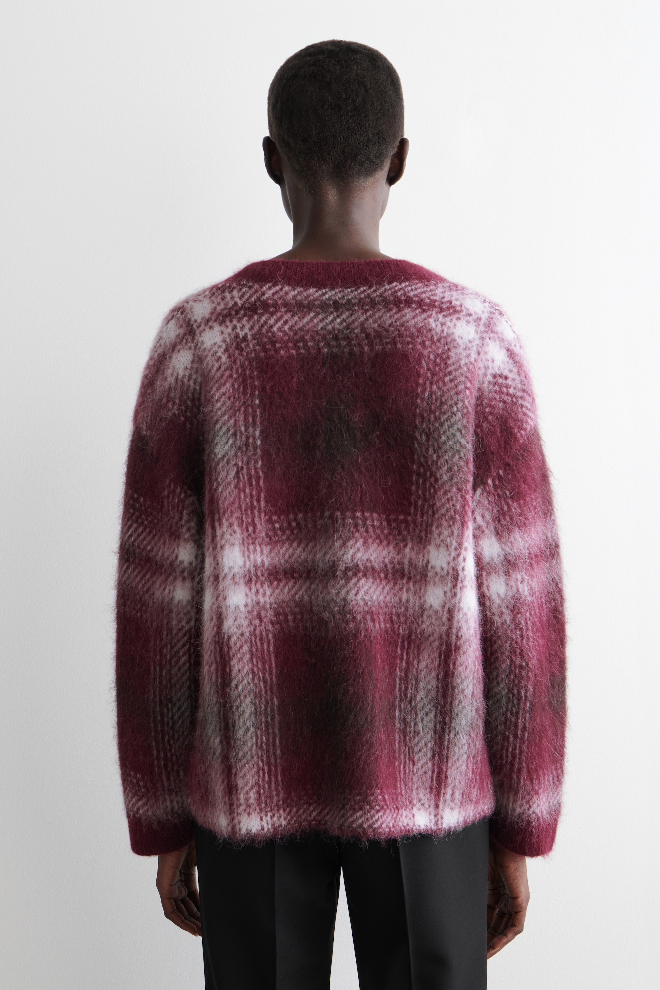Grösseres Bild ansehen: Ein flauschiger Pullover mit Rundhalsausschnitt wird von hinten gezeigt. Er zeigt ein großes Karomuster in Schattierungen von Kastanienbraun, Weiß und Dunkelgrau und weist eine sichtbar gebürstete, haarige Textur sowie lange Ärmel auf.