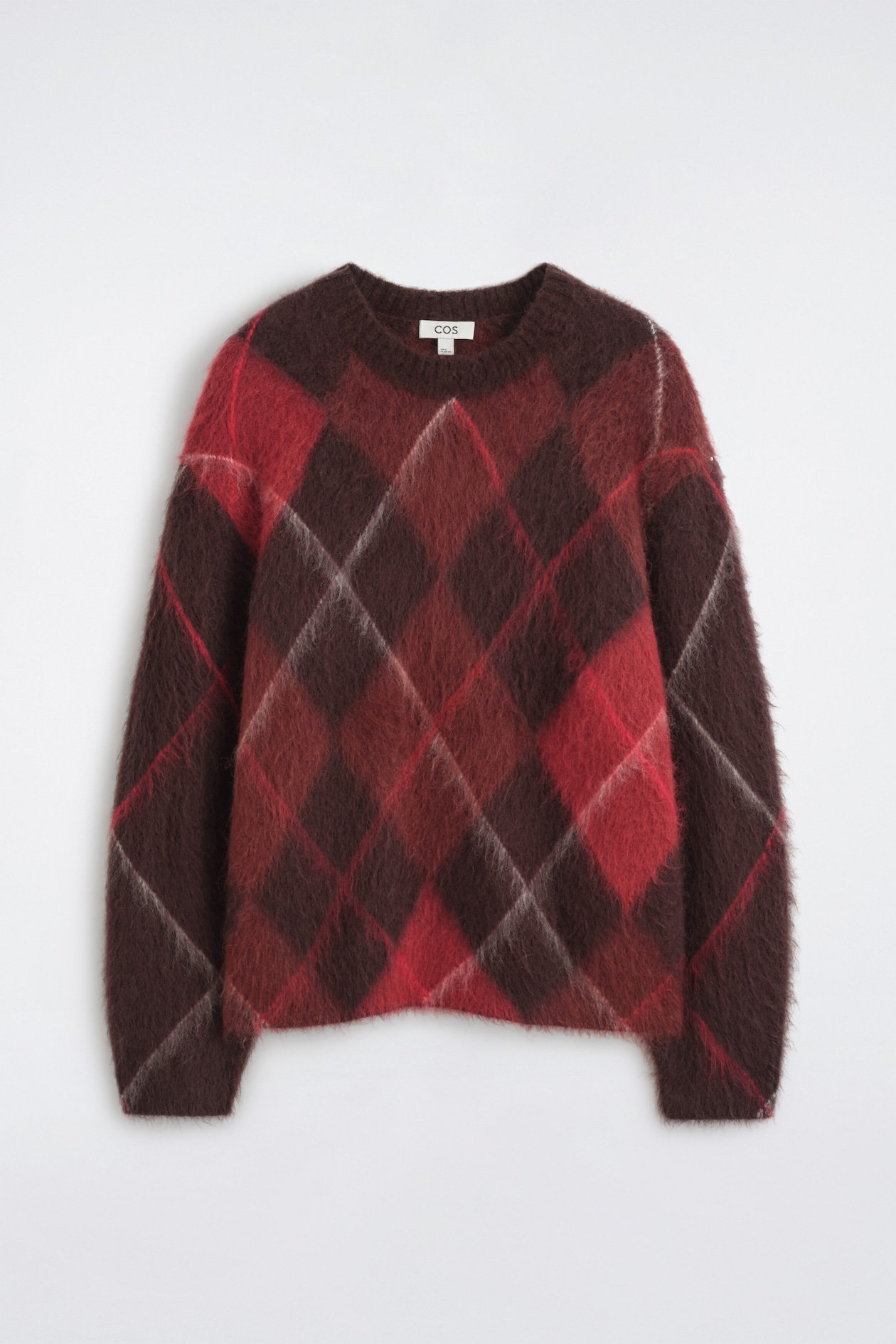 Ein langärmliger Pullover aus angerautem Strick ist von vorne zu sehen und zeigt ein grosses Argyle-Rautenmuster in Dunkelbraun-, Rot- und Hellgrautönen. Der Pullover hat einen gerippten Rundhalsausschnitt und eine weiche, flauschige Textur durchgehend.