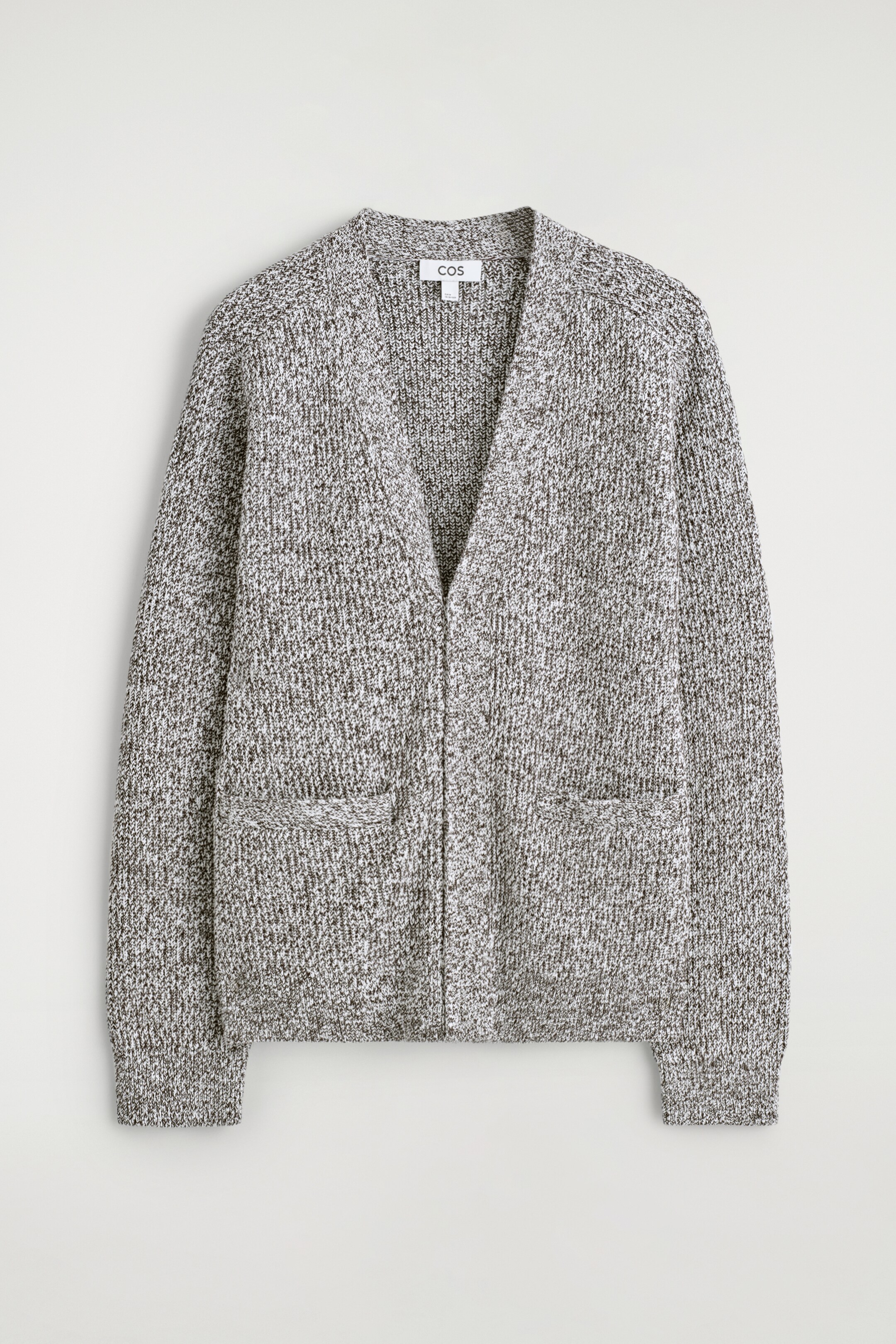 Agrandir l'image: Un cardigan en maille mélangée gris et blanc se présente comme un modèle FRONT, avec un col en V, un devant fermé sans attaches visibles, deux poches passepoilées horizontales sur le bas du devant, et des poignets et un ourlet côtelés.