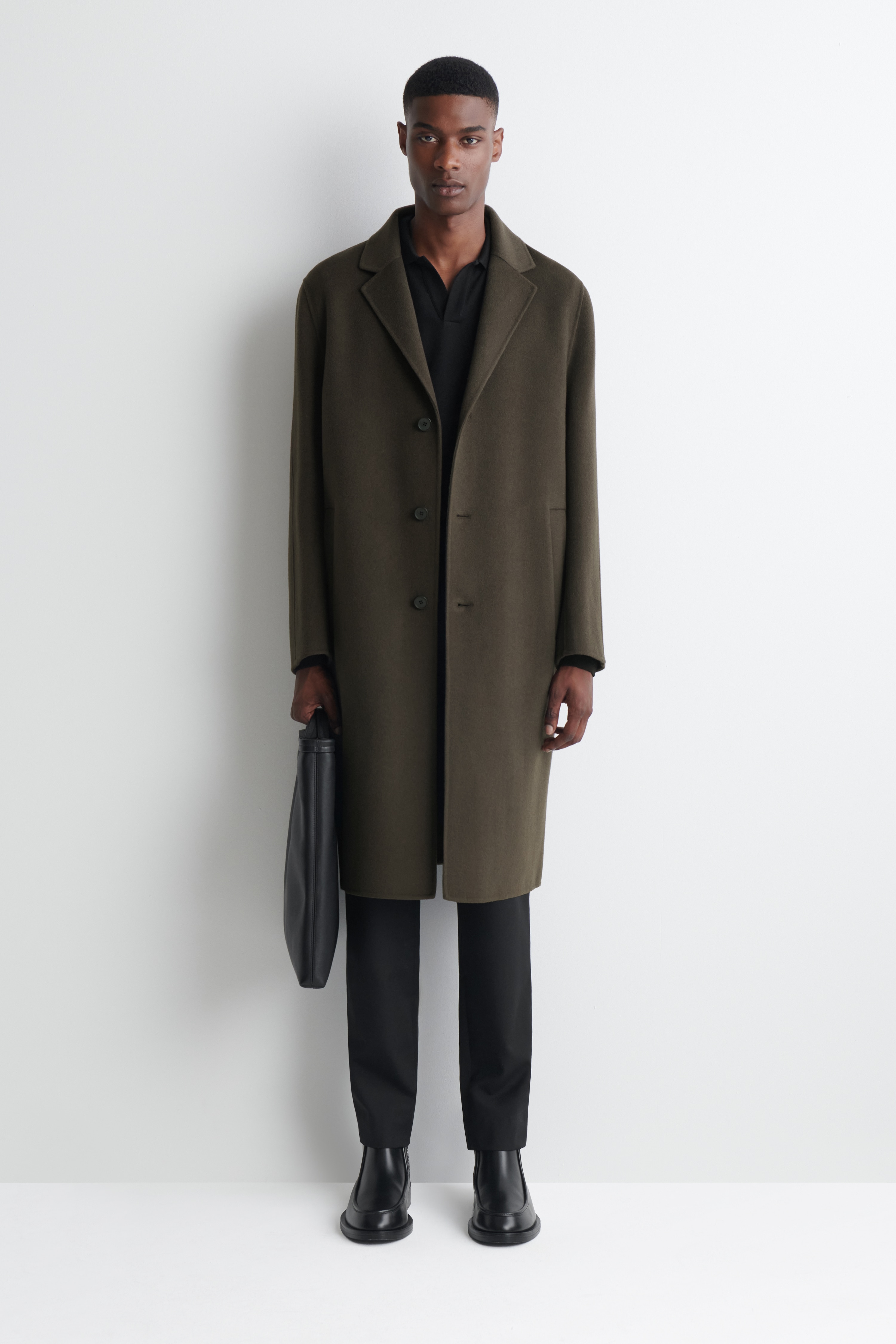 KabÃ¡t Tailored Double-Faced Wool-Blend visÃ­ ÄelnÄ, a ukazuje tmavÄ olivovÄ zelenou barvu, klopovÃ© lÃ­mce s vÃ½stÅihem do Å¡piÄky a jednoÅadÃ© tÅÃ­knoflÃ­kovÃ© zapÃ­nÃ¡nÃ­. MÃ¡ svislÃ© liÅ¡tovÃ© kapsy na kaÅ¾dÃ© stranÄ a dlouhÃ© rukÃ¡vy, ÄÃ­mÅ¾ vytvÃ¡ÅÃ­ Äistou, strukturovanou siluetu.