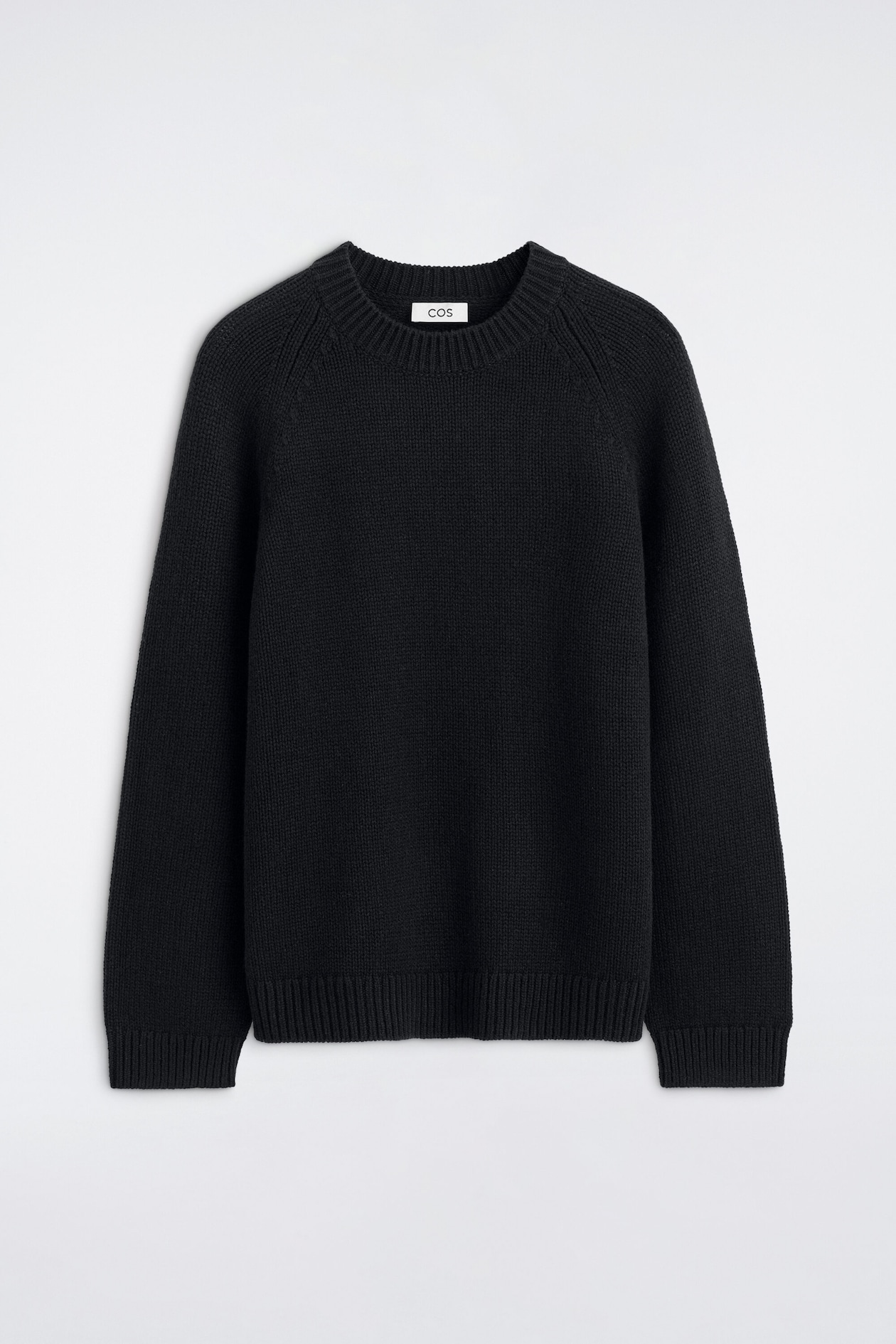 A black chunky-knit jumper is shown from the front, featuring a ribbed crew neck, rounded raglan sleeves, and ribbed cuffs and hem.