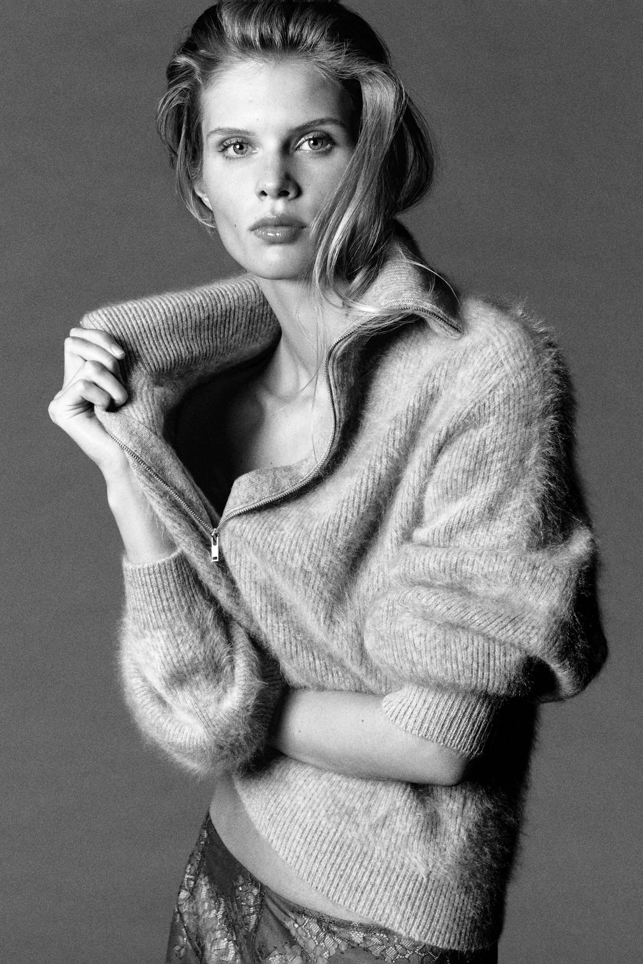 A cashmere sweater in a brushed, textured knit is shown from the front, highlighting its relaxed silhouette. The sweater features a high funnel neck with a metallic half-zip closure, ribbed cuffs, and a ribbed hem. A cashmere sweater in a brushed, textured knit is shown from the front, highlighting its relaxed silhouette. The sweater features a high funnel neck with a metallic half-zip closure, ribbed cuffs, and a ribbed hem.