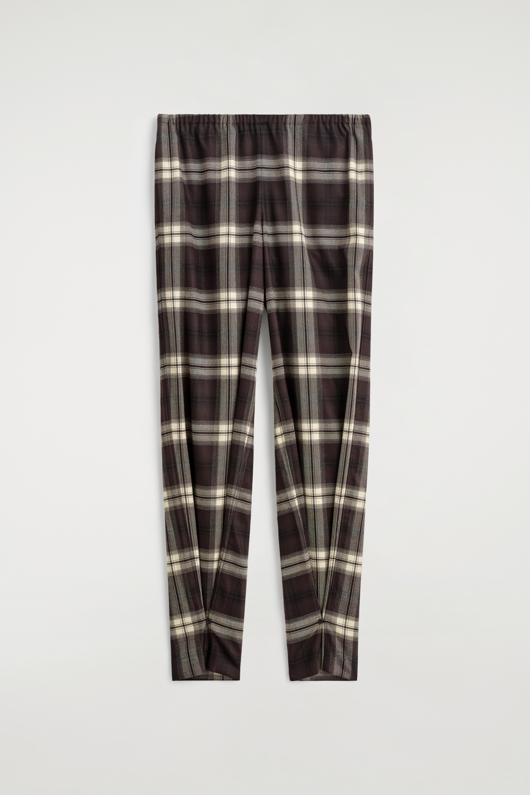 Agrandir l'image: Un pantalon affiche un motif à carreaux de couleur marron foncé, crème et gris, présenté de face. Le pantalon présente une taille élastiquée, une silhouette à jambes fuselées et des passants boutonnés aux chevilles qui resserrent le tissu.