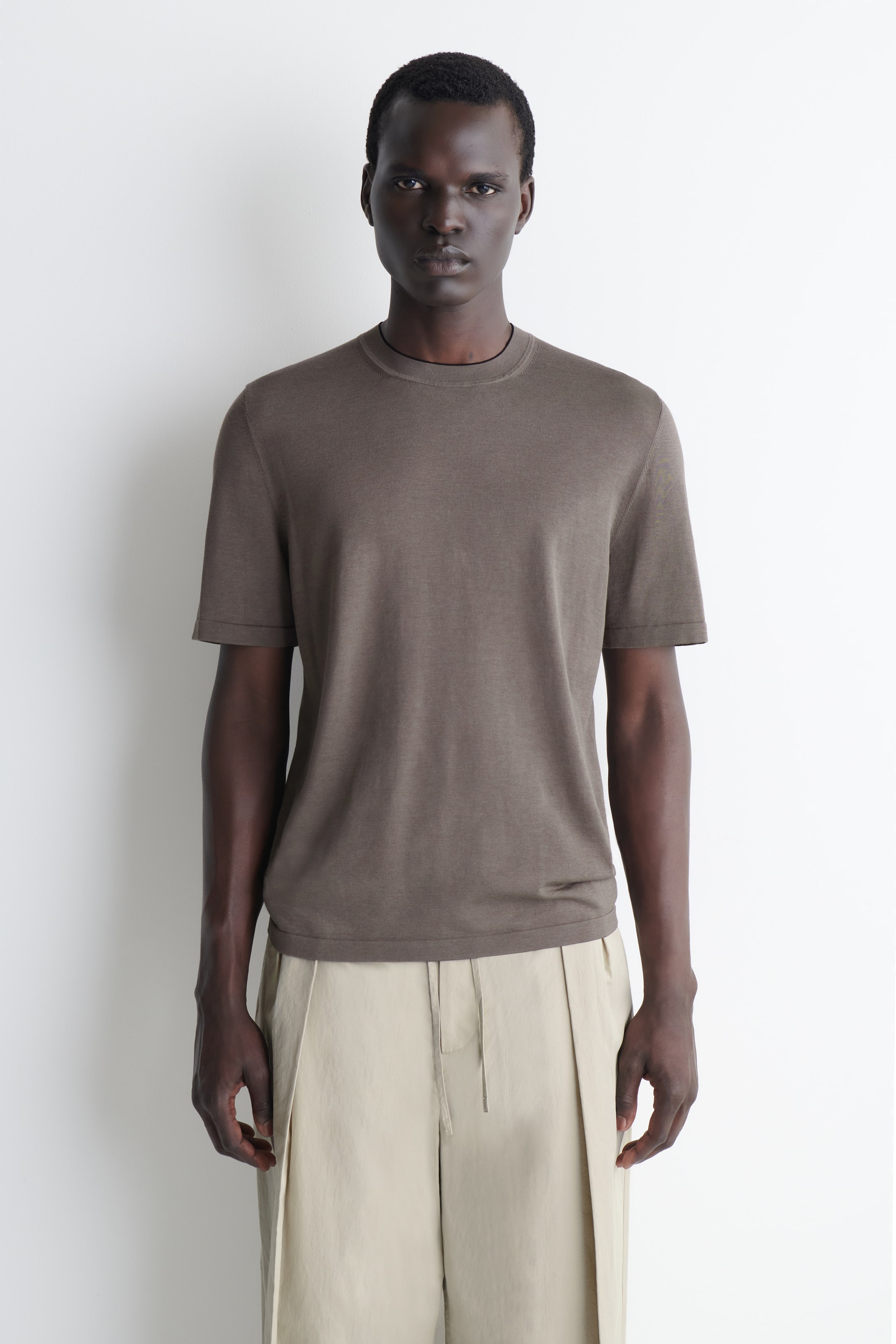 Größeres Bild ansehen: Ein braunes T-Shirt mit kurzen Ärmeln verfügt über einen Rundhalsausschnitt, eine glatte, feine Strickstruktur und kurze Ärmel, die oberhalb des Ellbogens enden. Es präsentiert einen geraden Saum und eine gerade Silhouette aus der Vorderansicht.