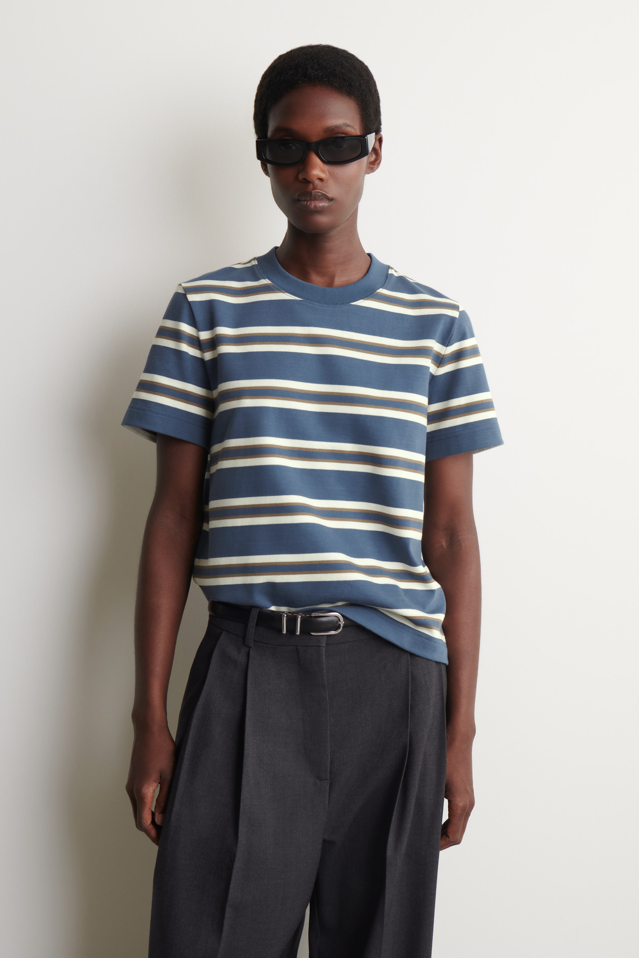 View larger image: The striped t-shirt features a blue body with horizontal white and khaki stripes of varying widths, a crew neck, and short sleeves. It presents a relaxed fit from the front.