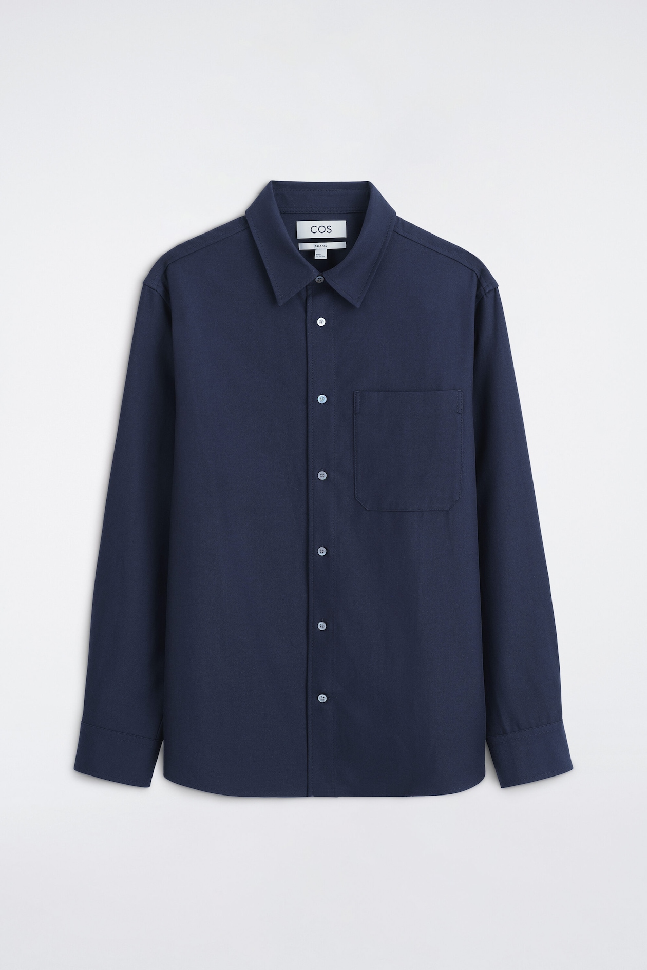 The relaxed twill shirt is shown from the front in navy blue, featuring a classic point collar, a button-up front with light-coloured buttons, and a single chest patch pocket. The long-sleeved shirt has a relaxed fit with buttoned cuffs and a straight hem.