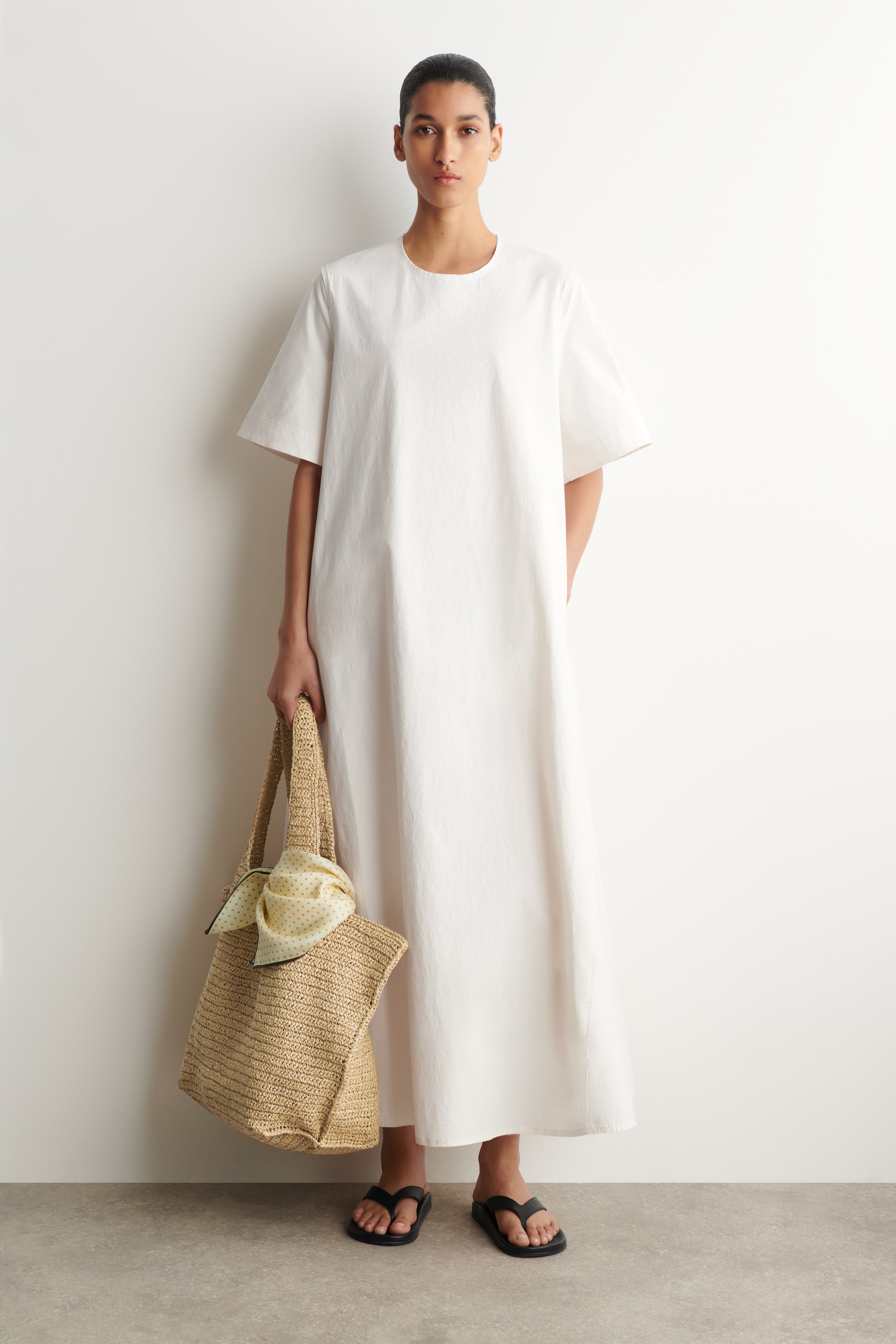 Ver imagen más grande: Se lleva un vestido maxi blanco de corte holgado, que presenta un escote redondo y mangas cortas amplias, con el dobladillo que se extiende hasta los tobillos.