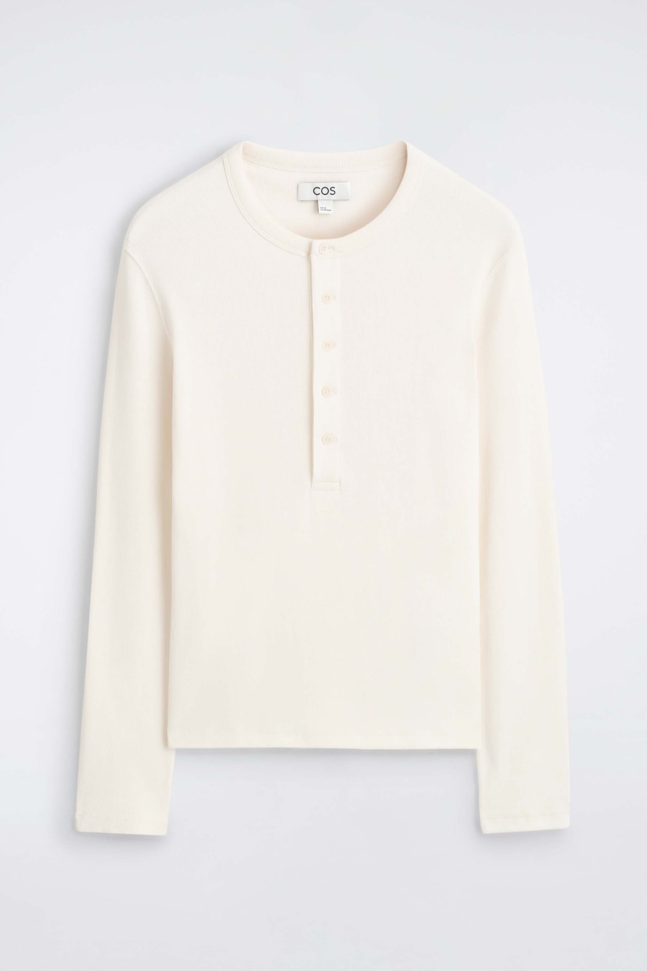 A slim ribbed cotton long-sleeved Henley T-shirt is shown from the front in an off-white colour, featuring a round neckline and a central front placket with five matching buttons. The garment displays a fine ribbed texture throughout the body and long sleeves.