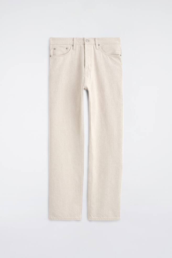 Ein Paar ecrufarbene Jeans mit geradem Bein ist von vorne zu sehen und zeigt eine klassische Five-Pocket-Konstruktion, GÃ¼rtelschlaufen und einen zentralen Knopfverschluss. Das Design betont eine klare, strukturierte Silhouette mit gerade geschnittenen Beinen. - 1