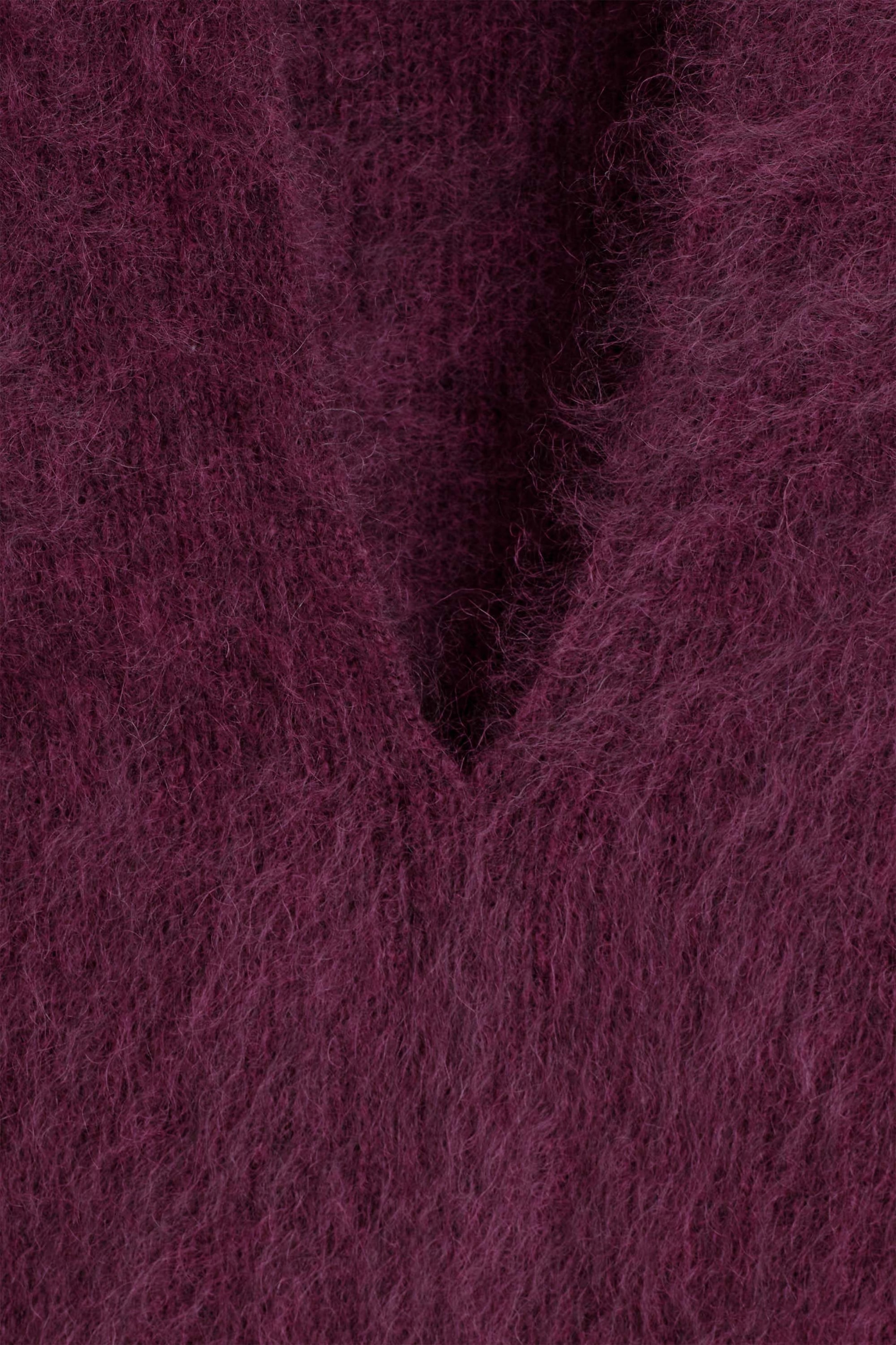 This close-up view of the draped brushed merino wool top in a deep plum color highlights its soft, fuzzy knitted texture. The image focuses on the V-neckline, showing the long, fine fibers of the brushed material.
