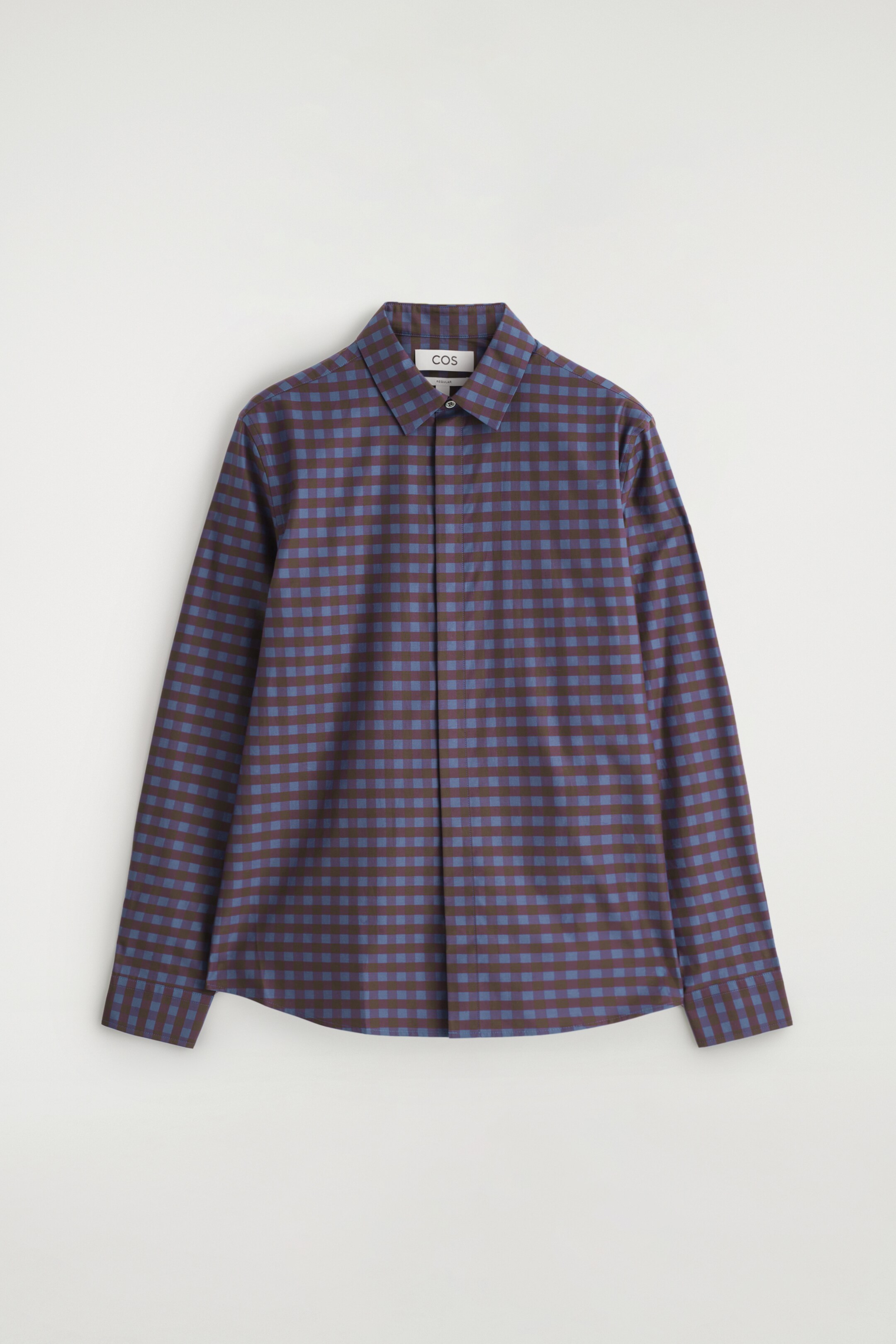 Ingrandisci l'immagine: Una camicia a maniche lunghe mostra la parte anteriore, con un colletto a punta, una chiusura a bottoni e un motivo a quadretti fini di quadrati marrone scuro e blu.