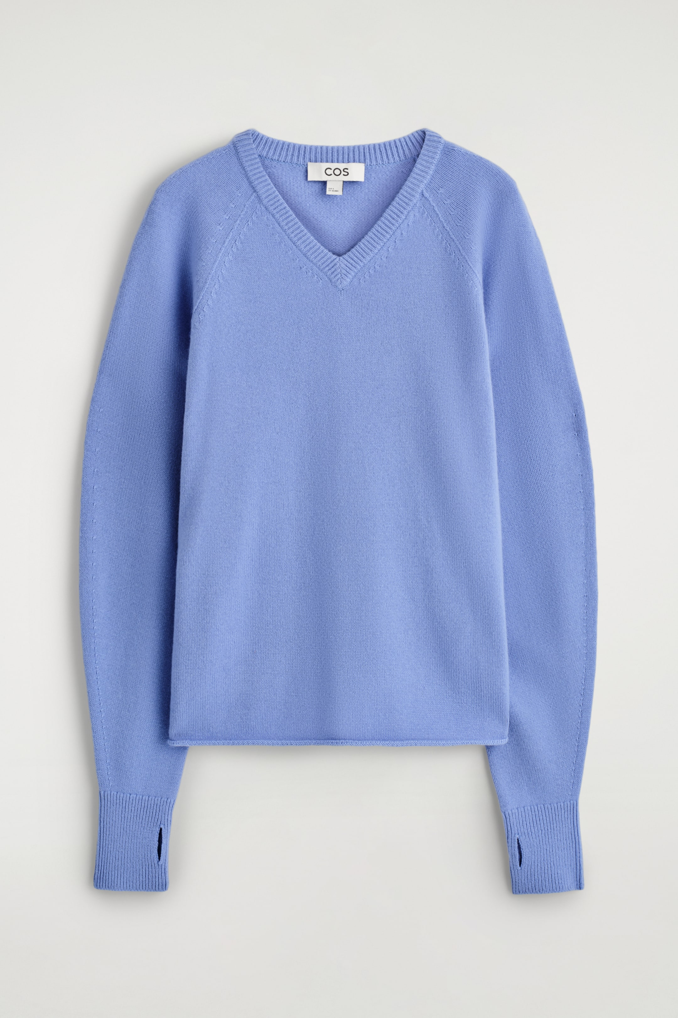 Visualizza immagine più grande: Un maglione in lana merino blu pervinca è presentato frontalmente, con uno scollo a V a coste, maniche raglan e un orlo arrotolato. I polsini presentano ritagli per i pollici.