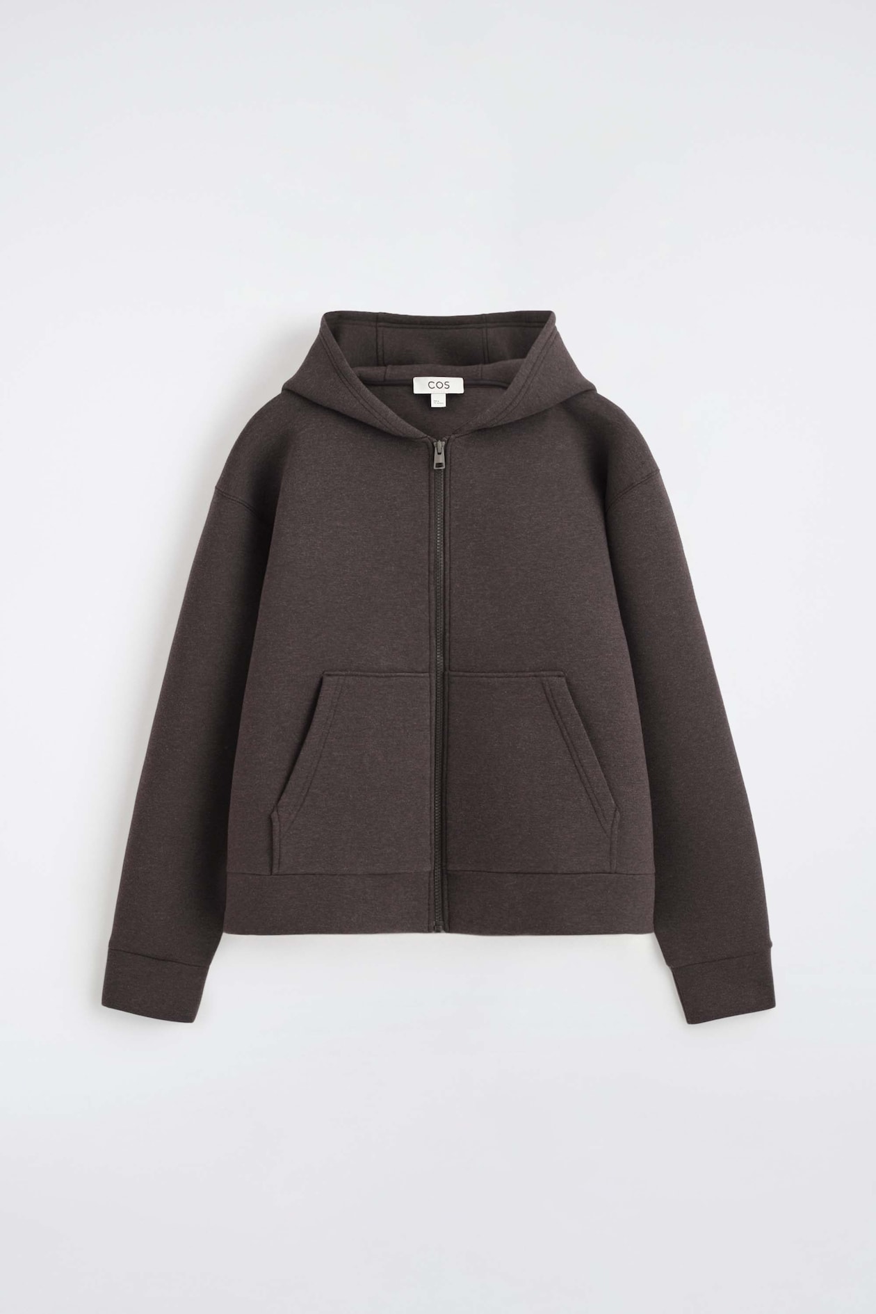 The oversized scuba jersey zip-up hoodie is shown from the front, featuring a dark brown hue, a structured hood, and a full-length centre zipper. It showcases dropped shoulders, ribbed cuffs, and a split kangaroo pocket on the front.