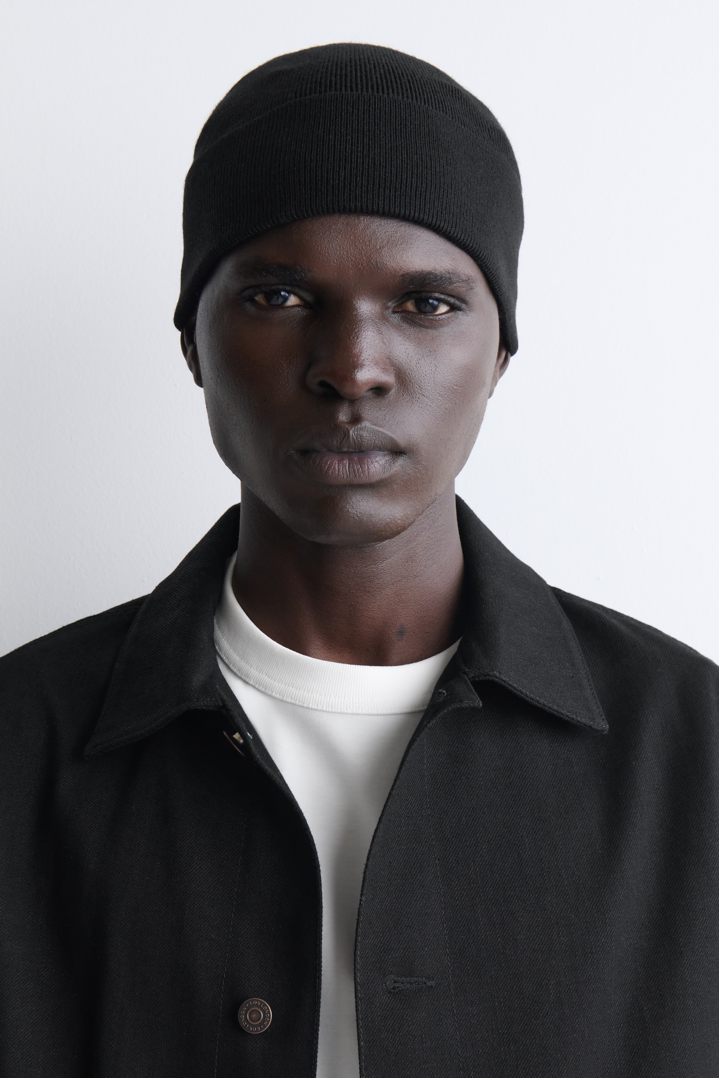 Czarna dzianinowa czapka beanie jest pokazana z przodu, eksponujÄc drobnÄ strukturÄ splotu, szeroki podwijany prÄÅ¼kowany mankiet oraz subtelne szwy modelujÄce na czubku.