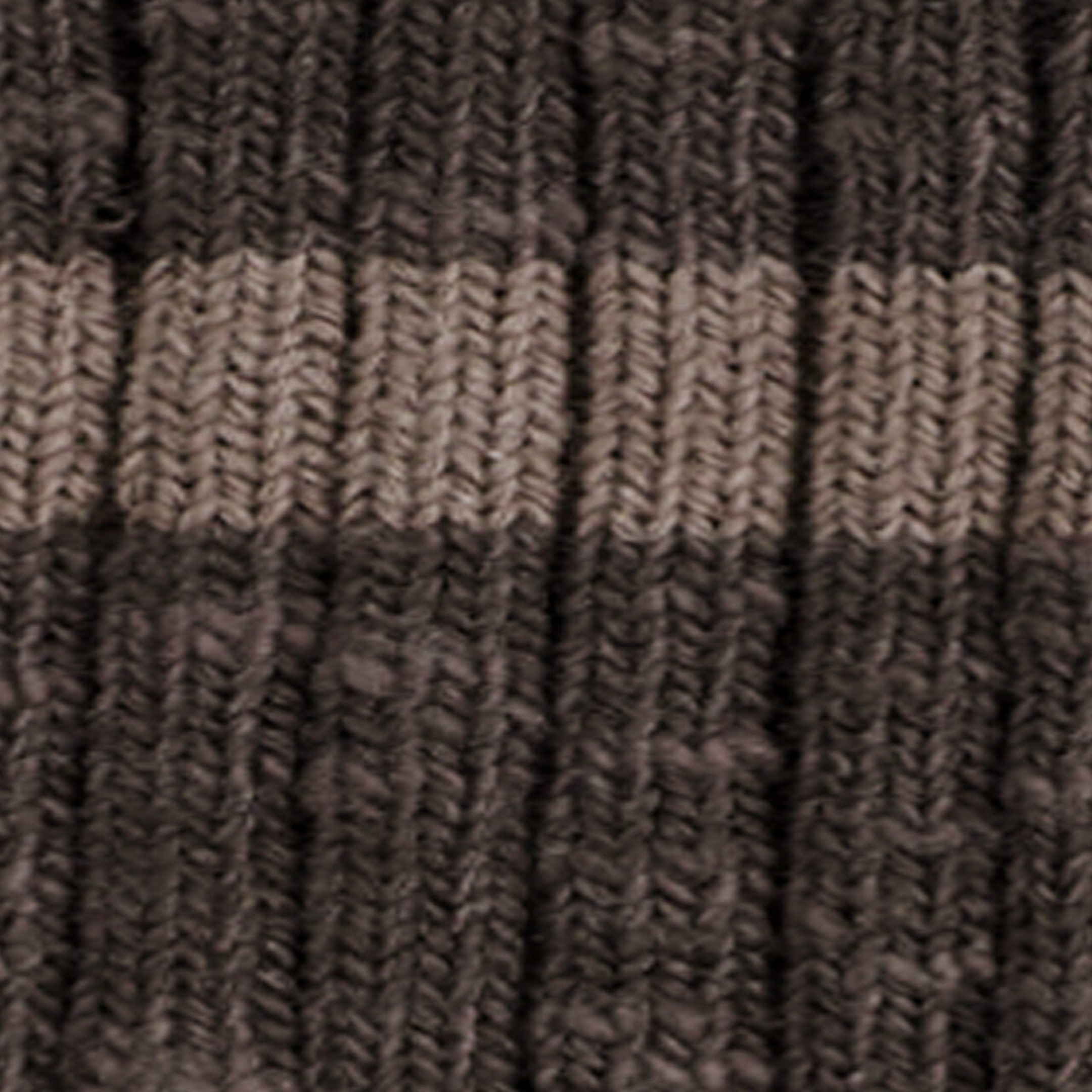 Un tissu tricoté côtelé présente un gros plan de sa structure texturée, avec des colonnes côtelées verticales et un motif à rayures horizontales en brun foncé et taupe pâle. Le fil épais affiche une texture douce et duveteuse sur l’ensemble du tricot.
