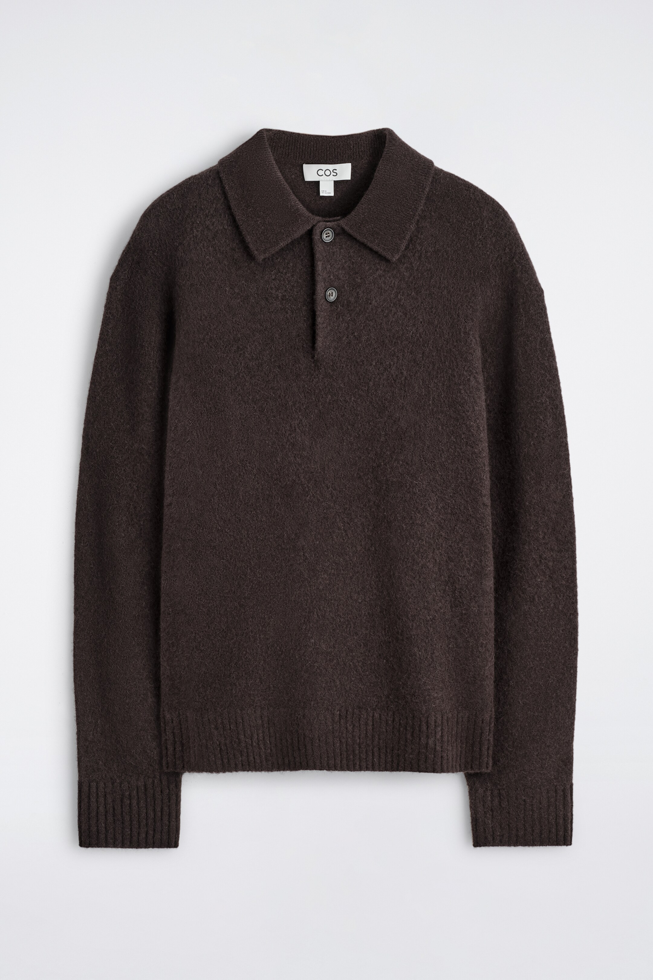 Agrandir l'image: Un polo en maille brun foncé est présenté, de face, mettant en valeur une coupe décontractée, un col standard et une patte à deux boutons avec des boutons foncés. Le polo arbore une texture visiblement brossée, et des poignets et un ourlet côtelés encadrent son bord inférieur et ses manches.
