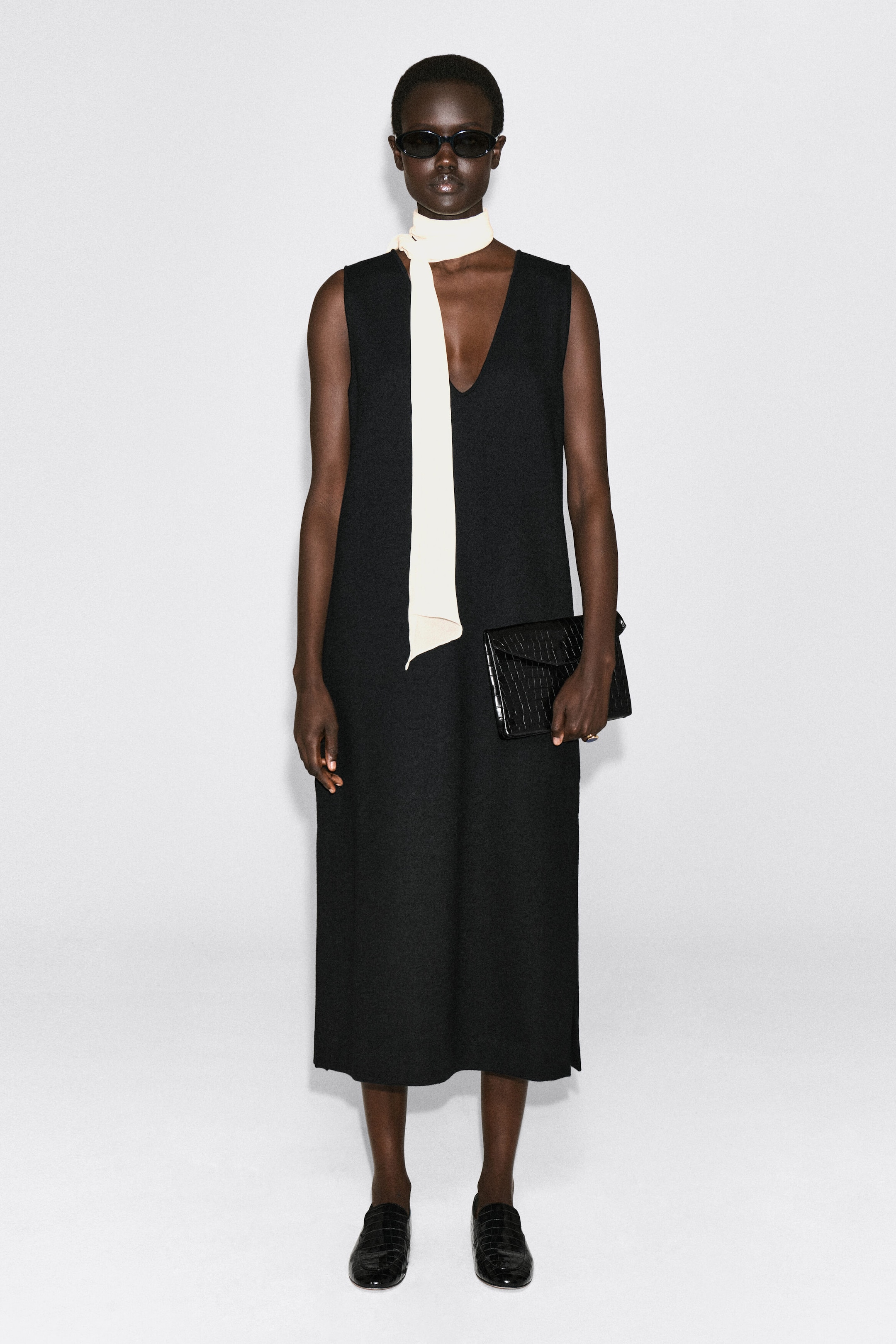 The black croc-effect leather Envelope Clasp Pouch is shown front-facing, highlighting its structured rectangular silhouette and glossy textured finish. It features a triangular, envelope-style fold-over flap. The black croc-effect leather Envelope Clasp Pouch is shown front-facing, highlighting its structured rectangular silhouette and glossy textured finish. It features a triangular, envelope-style fold-over flap.
