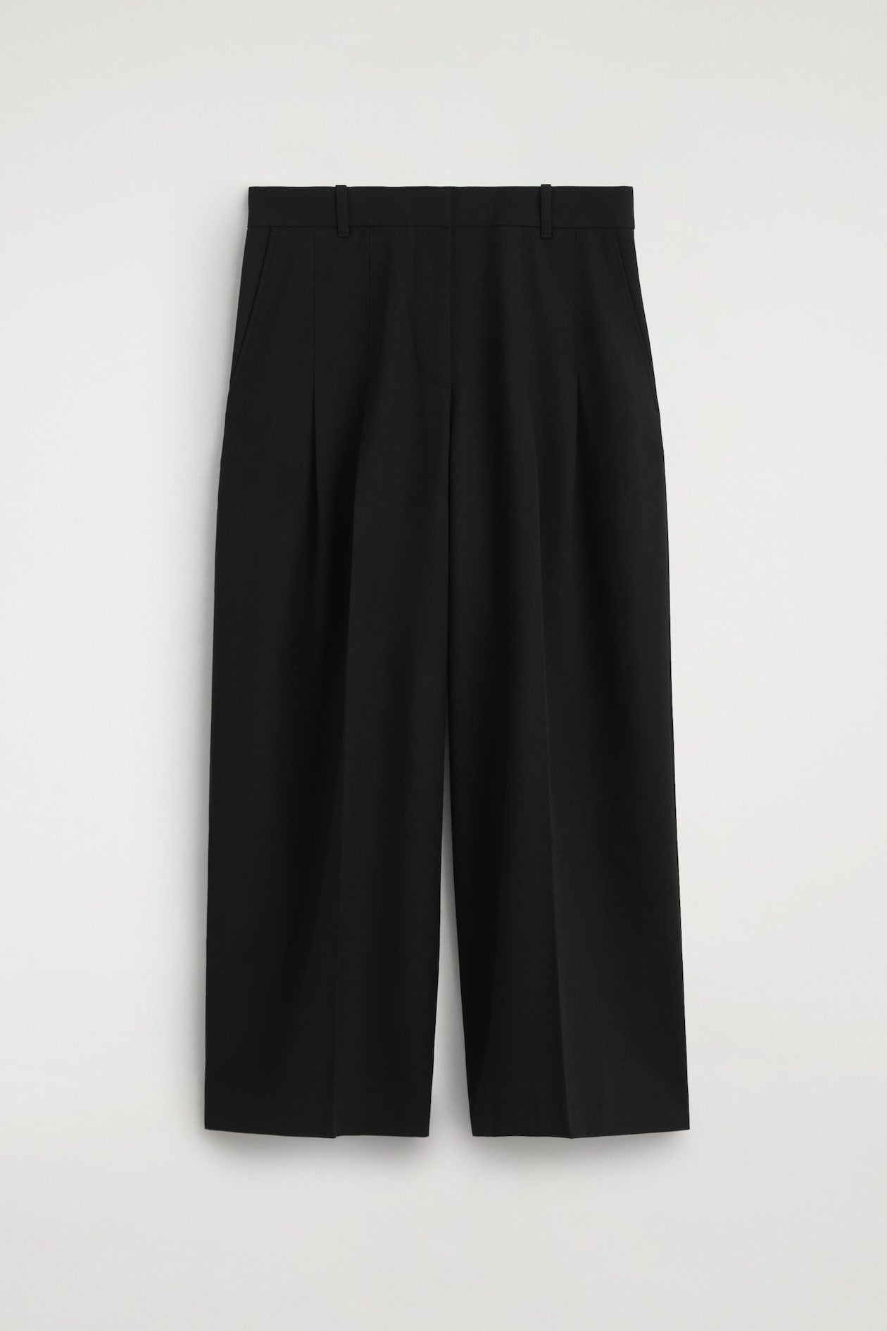 The black pleated wool-blend wide-leg trousers are shown from the front, featuring a structured waistband with belt loops, double front pleats, and sharp creases running down the wide legs.