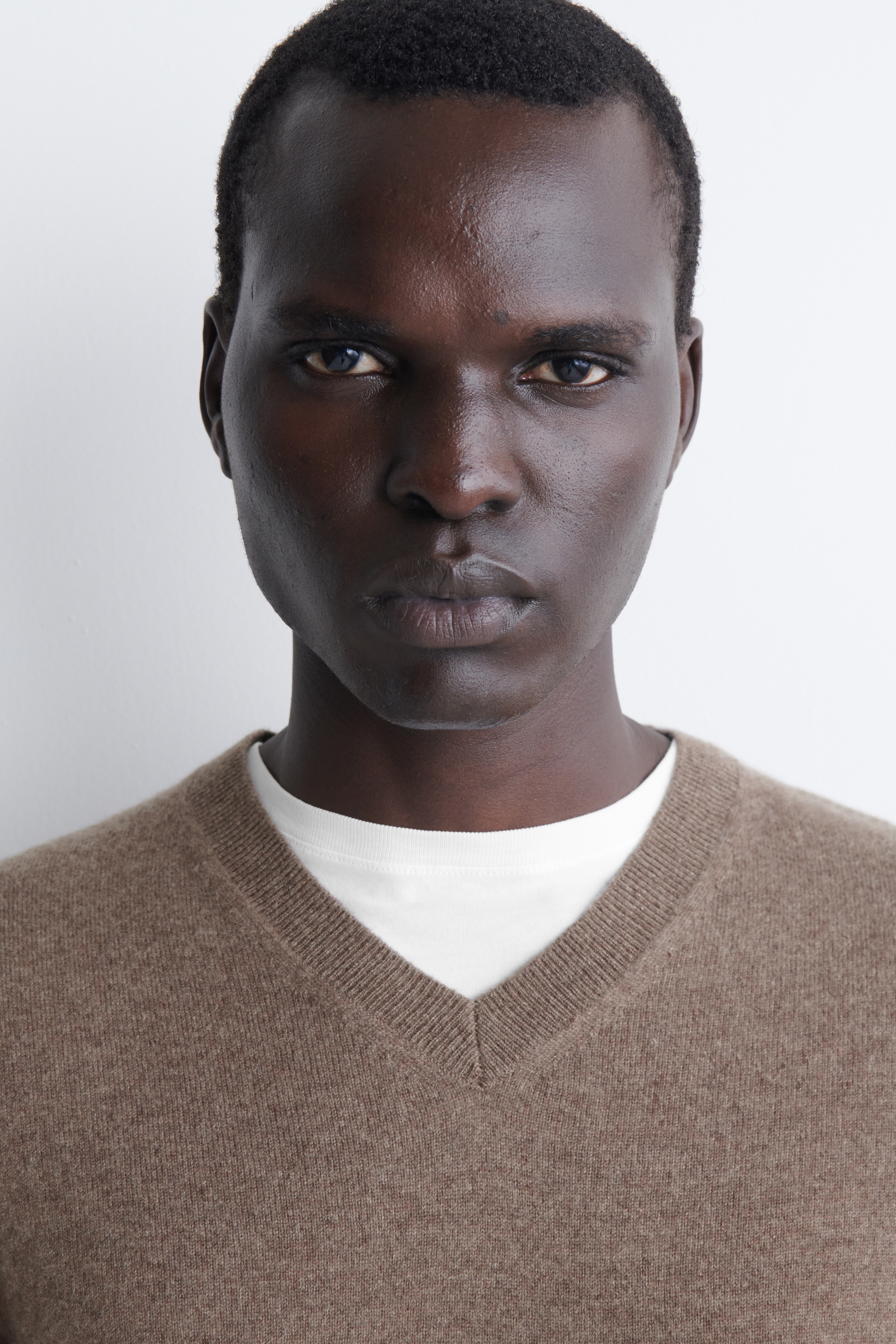 Un maglione in cashmere con scollo a V, in maglia testurizzata taupe-marrone, Ã¨ mostrato in una vista frontale. Il capo presenta uno scollo a V a coste, maniche lunghe con polsini a coste e un orlo a coste coordinato.