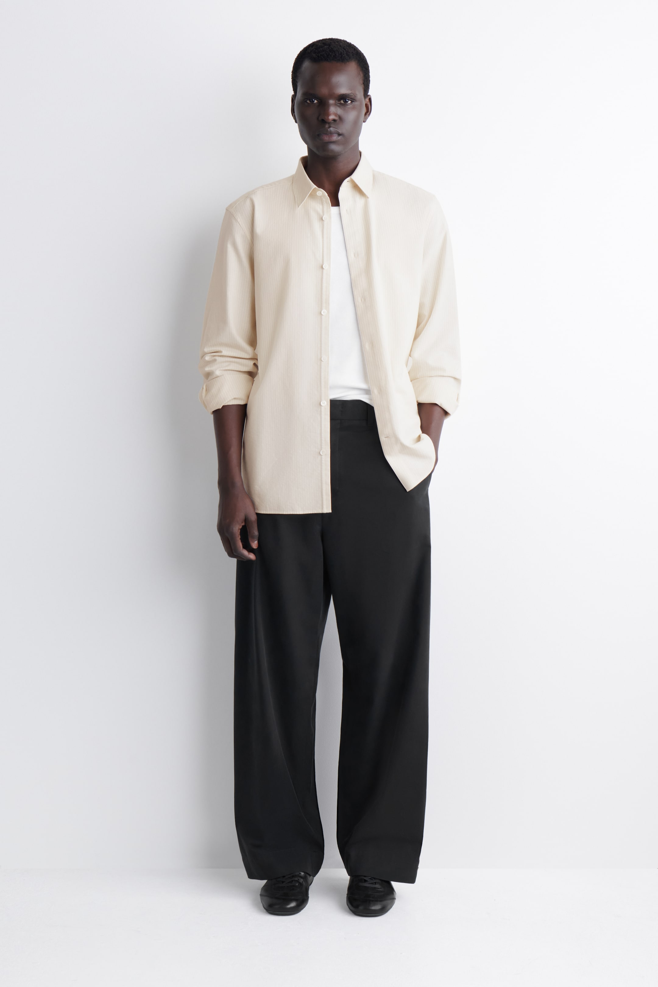 View larger image: Black wide-leg chinos are displayed from the front, showcasing a relaxed fit with belt loops. They are designed with visible side pockets and pressed creases running down the front of each leg.