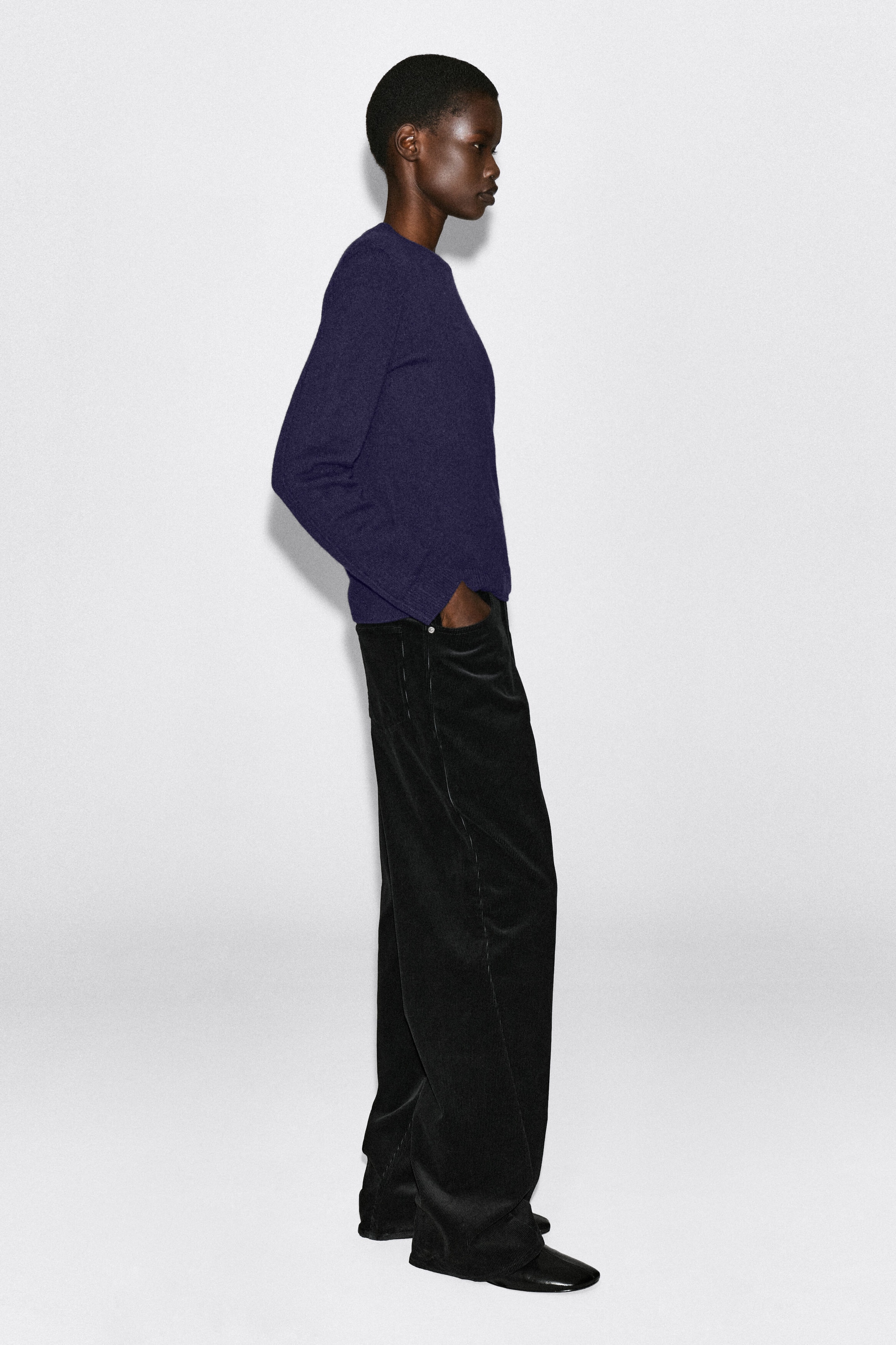 Le mannequin porte un pull col rond violet foncé, debout de profil, avec une main dans la poche d’un pantalon noir. Ce pull à manches longues présente une coupe regular et des finitions côtelées. Le mannequin porte un pull col rond violet foncé, debout de profil, avec une main dans la poche d’un pantalon noir. Ce pull à manches longues présente une coupe regular et des finitions côtelées.