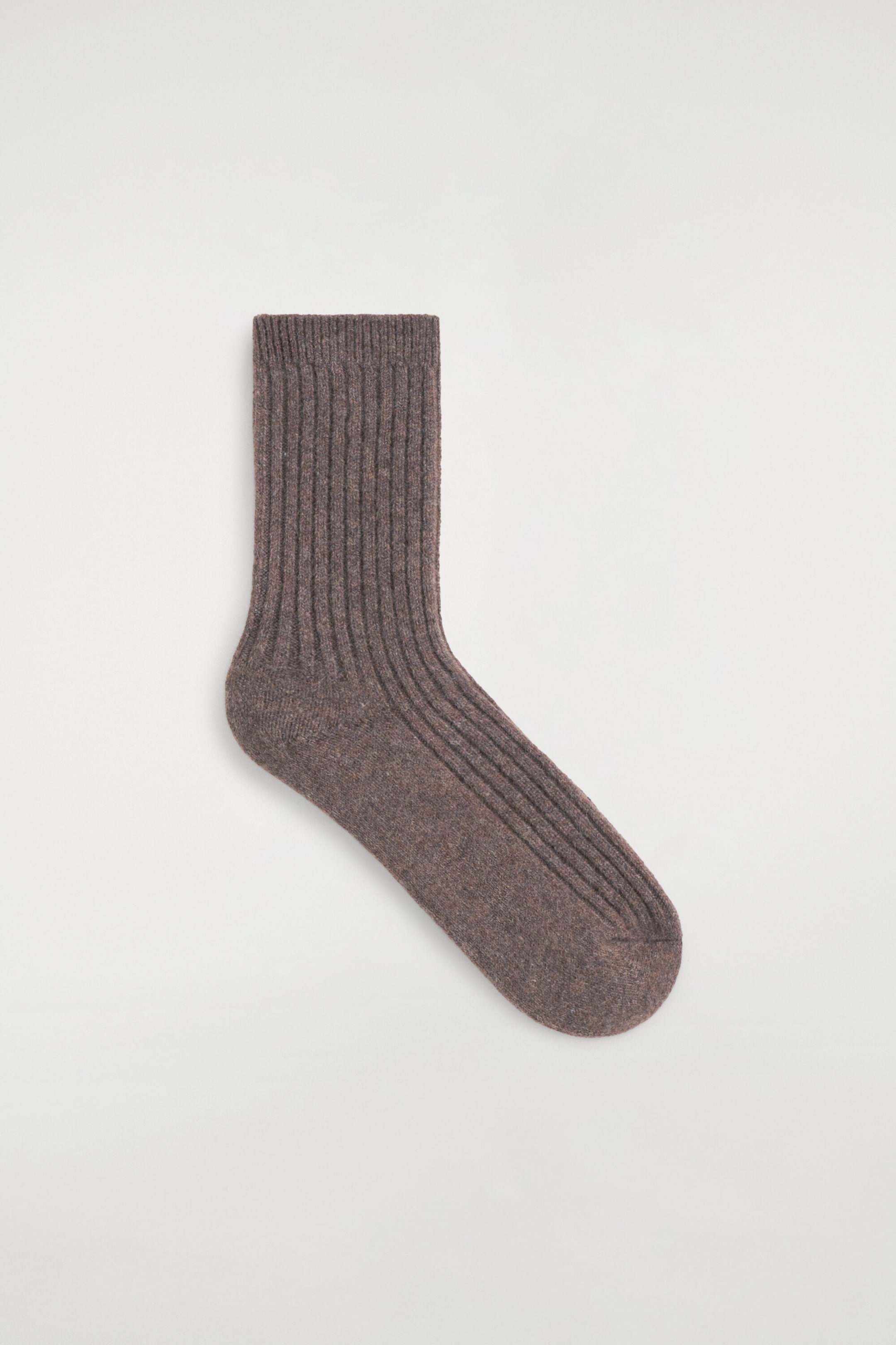 Une chaussette en cachemire côtelé, de couleur brun chiné, est posée à plat en vue de profil. La chaussette présente une texture tricotée côtelée verticale distincte le long de la jambe et du dessus du pied, avec un tricot lisse au niveau du talon et des orteils. Une chaussette en cachemire côtelé, de couleur brun chiné, est posée à plat en vue de profil. La chaussette présente une texture tricotée côtelée verticale distincte le long de la jambe et du dessus du pied, avec un tricot lisse au niveau du talon et des orteils.