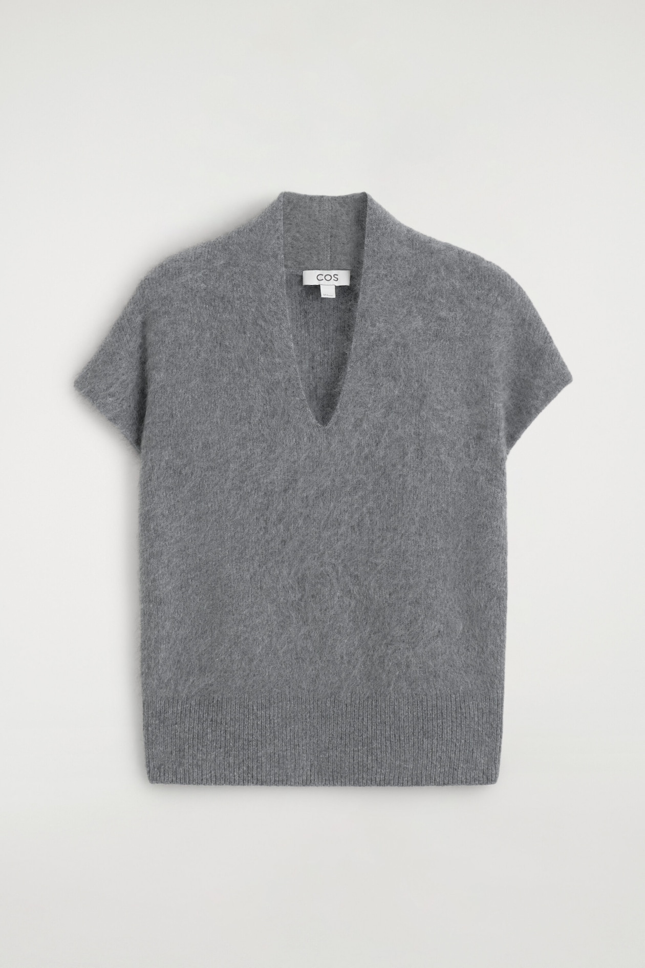 Un haut gris en tricot brossé est présenté de face, avec un profond col en V incurvé, des manches courtes à emmanchure tombante et un large ourlet côtelé.
