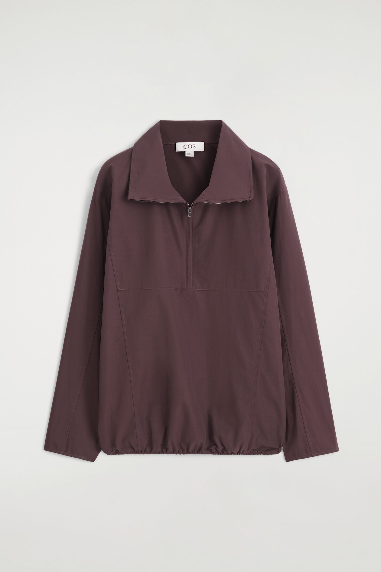 This dark plum half-zip pullover is shown from the front, featuring a wide pointed collar with a silver-tone zip closure and long sleeves with dropped shoulders. It features topstitched seams across the front and an elasticized, gathered hem.