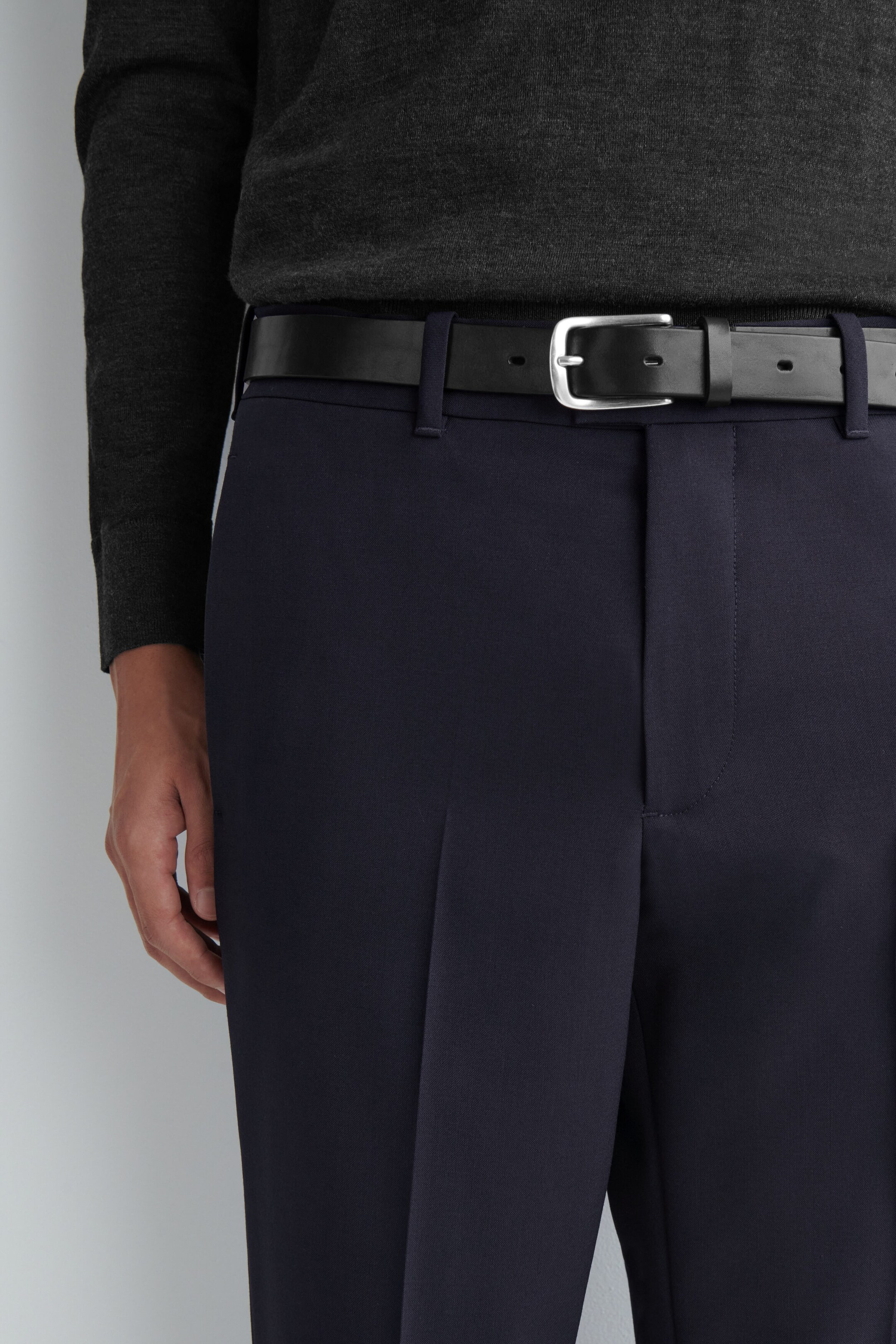 Le mannequin porte un pantalon droit slim en laine bleu marine foncé, doté de passants de ceinture et d’un devant épuré avec des plis marqués au fer. Une ceinture en cuir noir avec une boucle ton argent est passée dans la taille, retenant un pull en maille gris foncé rentré à l’intérieur. Le mannequin porte un pantalon droit slim en laine bleu marine foncé, doté de passants de ceinture et d’un devant épuré avec des plis marqués au fer. Une ceinture en cuir noir avec une boucle ton argent est passée dans la taille, retenant un pull en maille gris foncé rentré à l’intérieur.