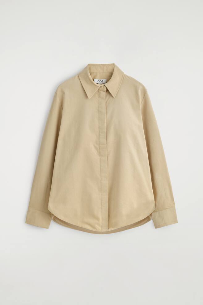 A beige cotton-corduroy shirt is presented from the front, displaying a regular fit, a pointed collar, a concealed button placket, long sleeves, and a curved hem. - 1