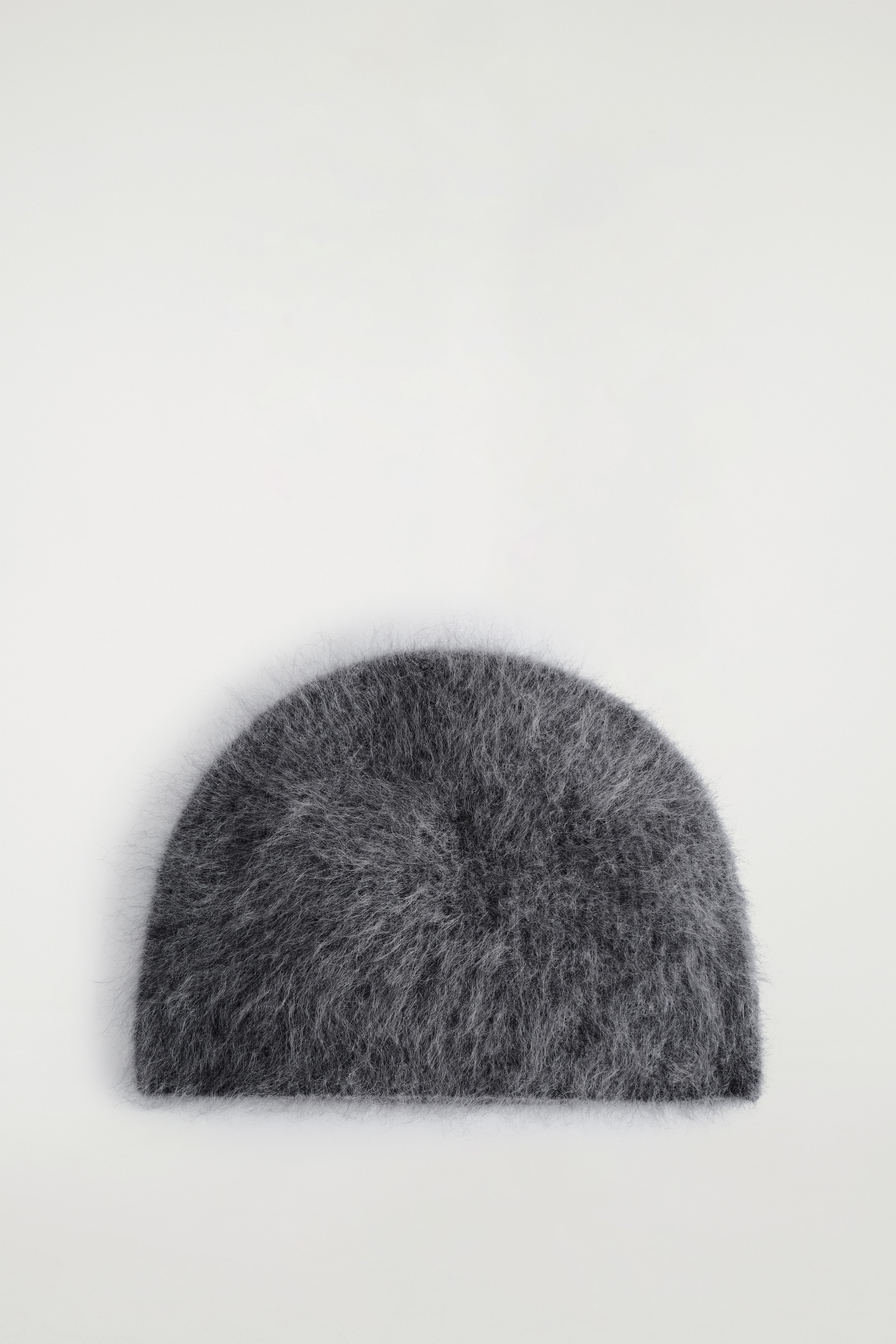 Agrandir l'image: Un bonnet en charbon est présenté de dessus, mettant en valeur sa texture duveteuse et brossée.