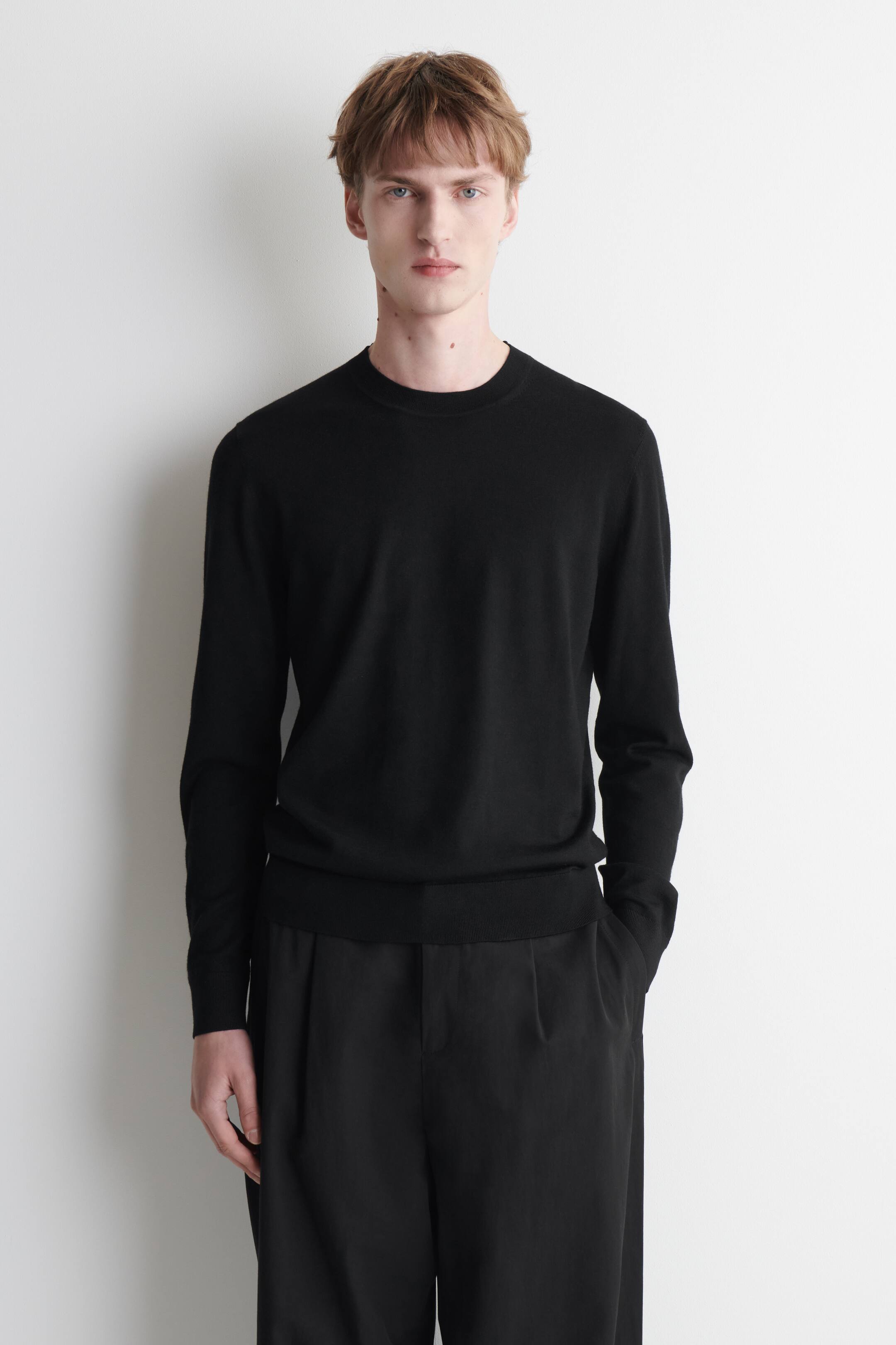 View larger image: A black crew neck sweater is shown from the front, featuring a fine knit texture, long sleeves, ribbed cuffs and a ribbed hem. The sweater has a slim fit silhouette.