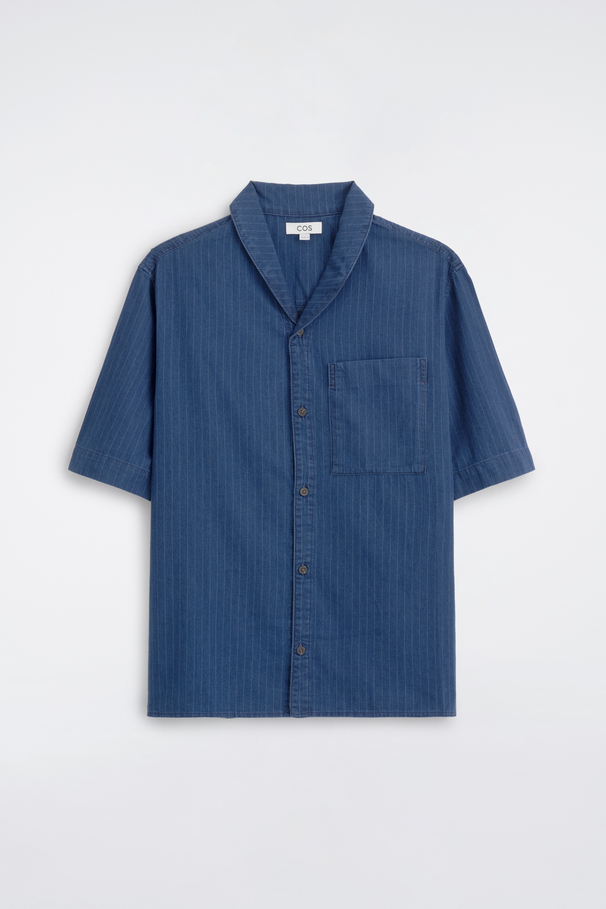 O cÄmaÈÄ din denim cu dungi fine Èi pantaloni scurÈi din denim asortaÈi, cu dungi fine Èi Ènur Ã®n talie, sunt purtate frontal, stilizate cu un tricou alb Ã®n straturi. CÄmaÈa cu mÃ¢necÄ scurtÄ evidenÈiazÄ un guler camp, un faÈÄ cu nasturi lÄsatÄ deschisÄ Èi un buzunar aplicat la piept, Ã®n timp ce pantalonii scurÈi asortaÈi oferÄ o croialÄ relaxatÄ, coordonatÄ.