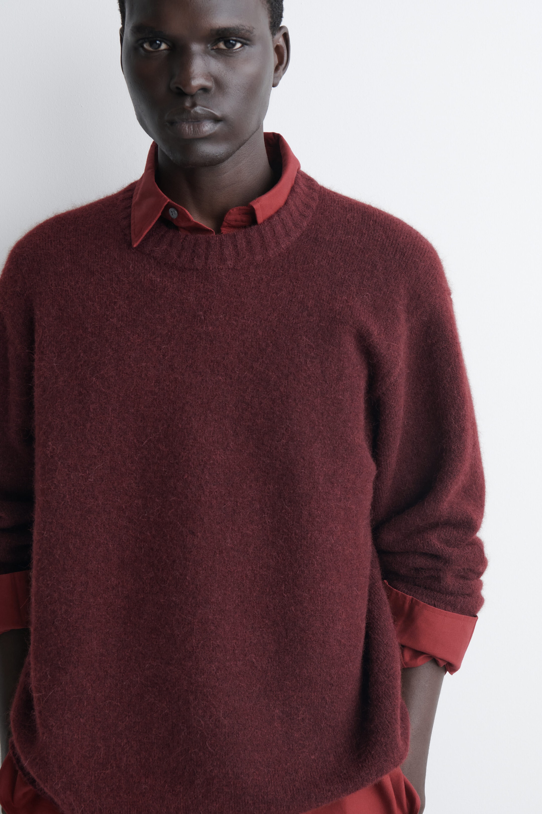 The burgundy oversized alpaca-blend crew-neck jumper is being worn facing front, showcasing its textured, fuzzy knit and relaxed fit. It is layered over a red collared shirt, with the collar and cuffs visible. The burgundy oversized alpaca-blend crew-neck jumper is being worn facing front, showcasing its textured, fuzzy knit and relaxed fit. It is layered over a red collared shirt, with the collar and cuffs visible.