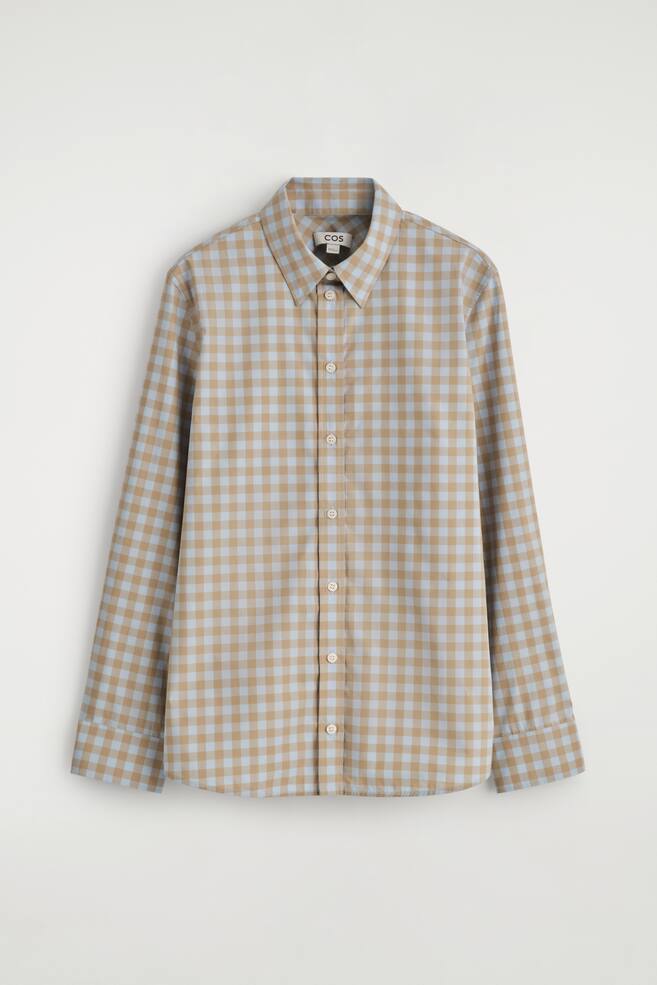 Una vista FRONTALE di una camicia a quadri vichy azzurro chiaro e marrone chiaro. Presenta un colletto a punta, maniche lunghe con polsini ampi e una chiusura frontale con bottoni chiari. - 1