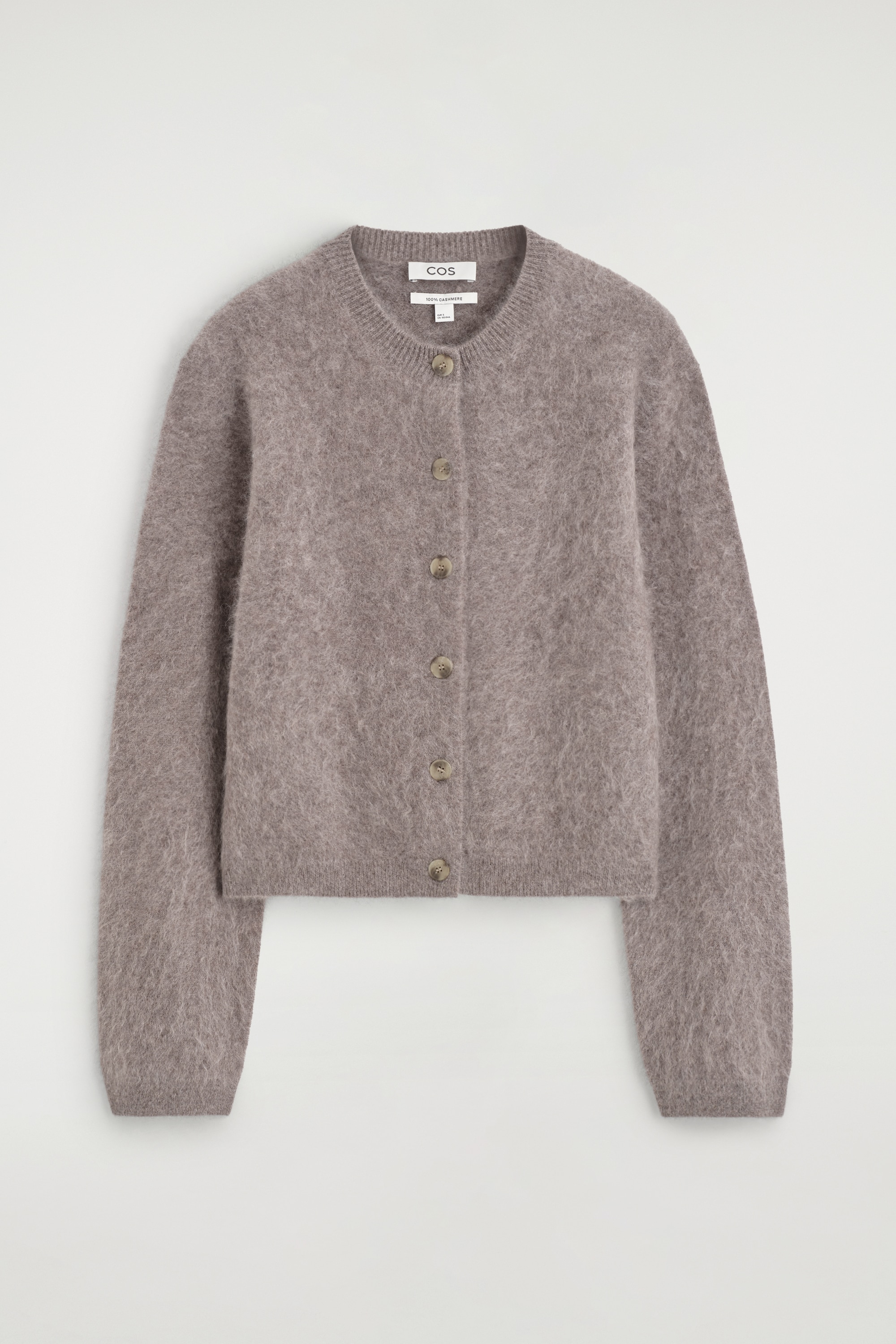 A brownish-grey fuzzy knit cardigan features a round neck and a button-front fastening with several light-coloured buttons. This loose-fitting, hip-length cardigan is worn open over a white top.
