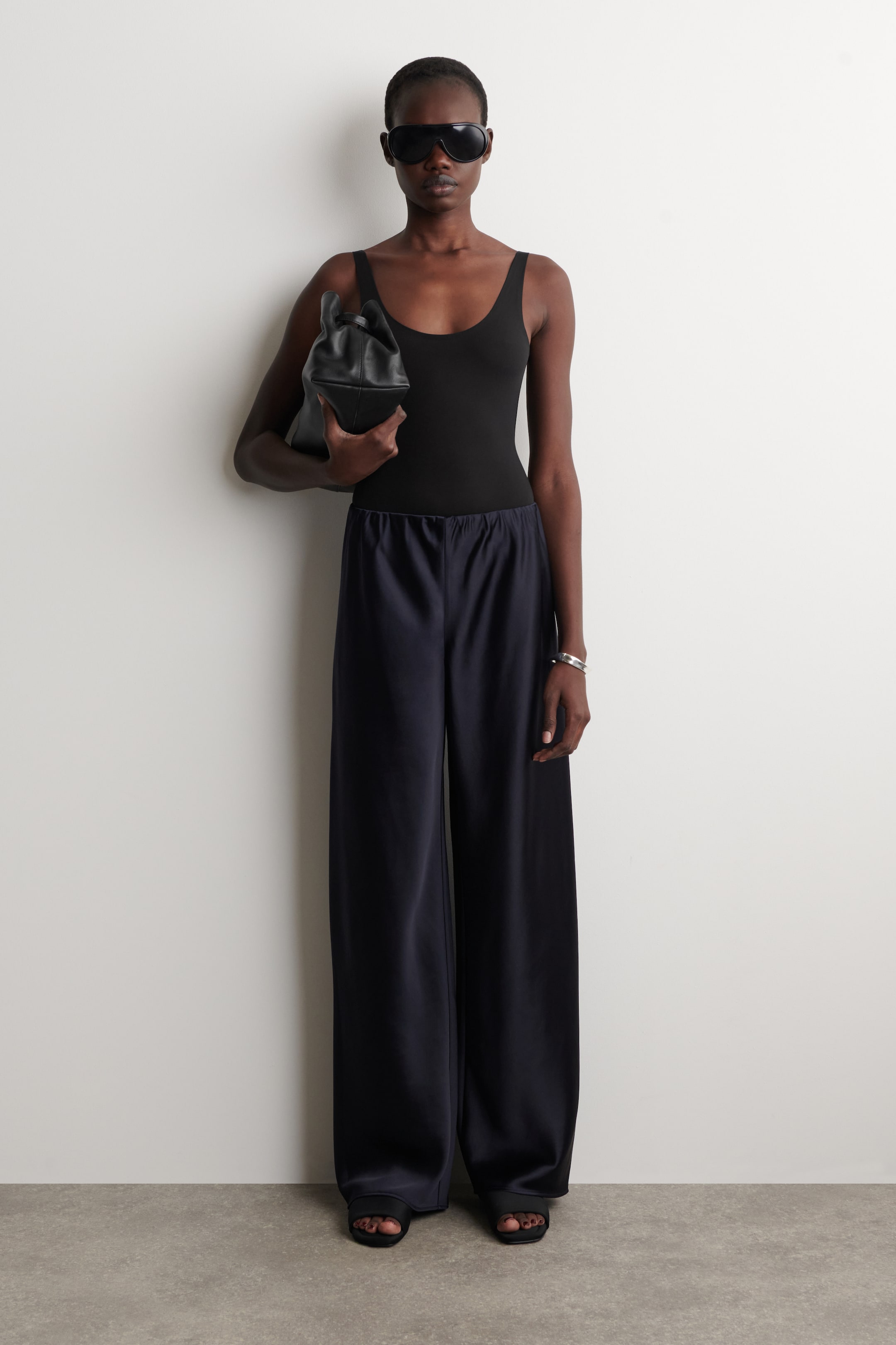 Agrandir l'image: Pantalon bleu marine à jambes larges doté d'une taille élastiquée et d'un tissu lisse et brillant, offrant une silhouette décontractée et tombant jusqu'au sol.
