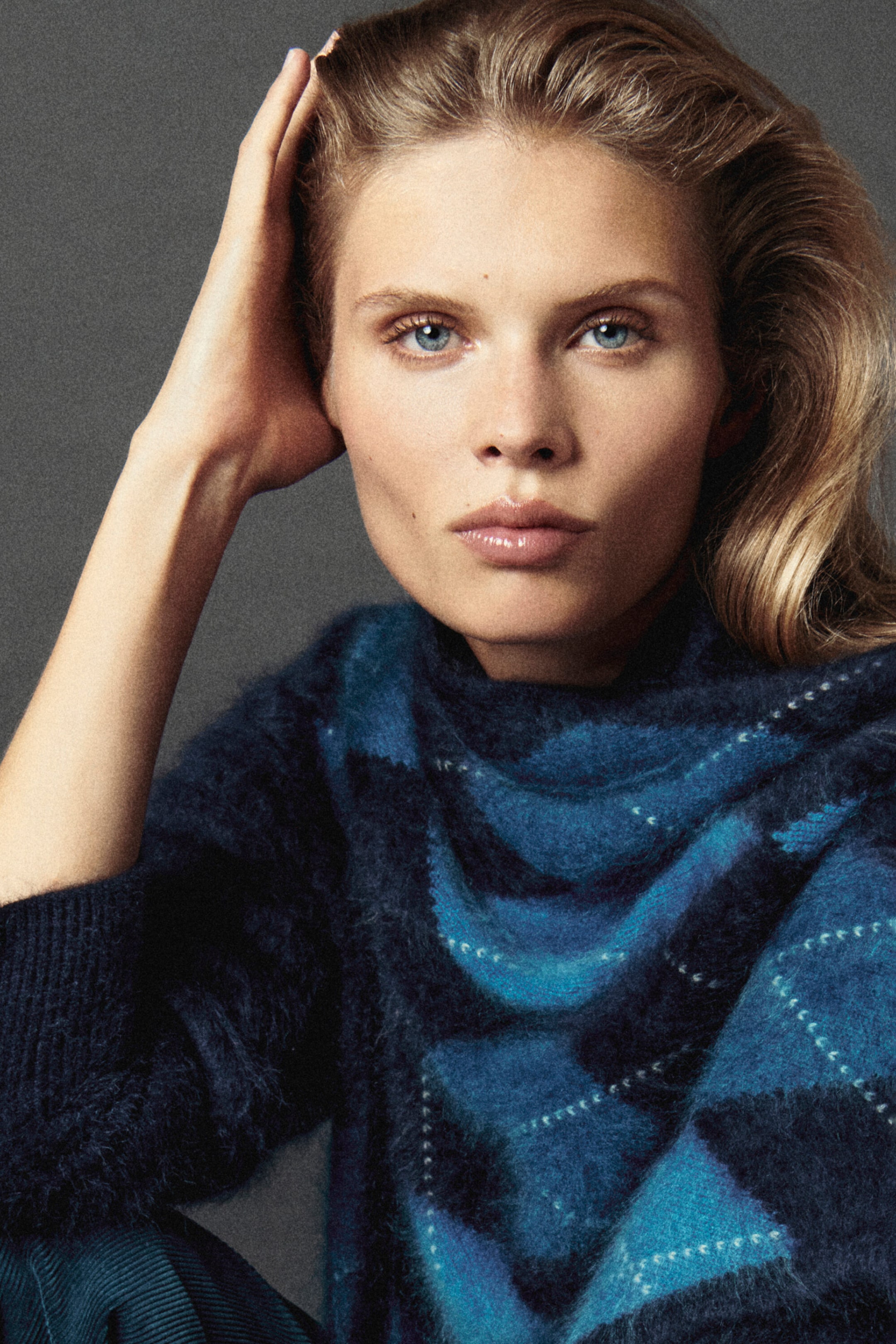 The argyle brushed cashmere triangle scarf in shades of blue and navy is worn draped around the neck, showcasing its soft, fuzzy texture and geometric pattern. It is layered over a matching brushed-knit jumper, highlighting its cosy fit and draped style from the front. The argyle brushed cashmere triangle scarf in shades of blue and navy is worn draped around the neck, showcasing its soft, fuzzy texture and geometric pattern. It is layered over a matching brushed-knit jumper, highlighting its cosy fit and draped style from the front.