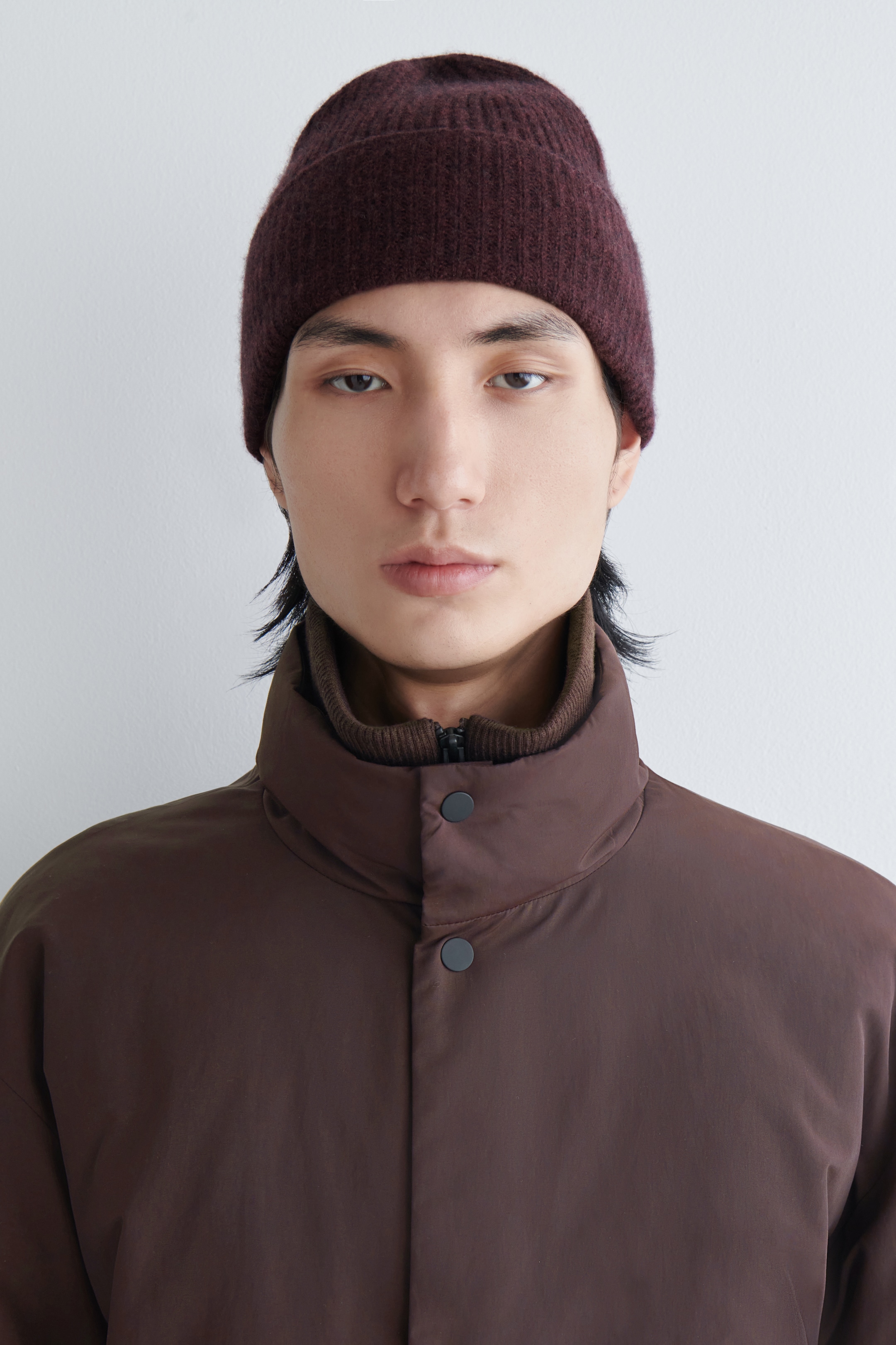 View larger image: A dark burgundy ribbed beanie is being worn by the model, covering the top of the model's head.