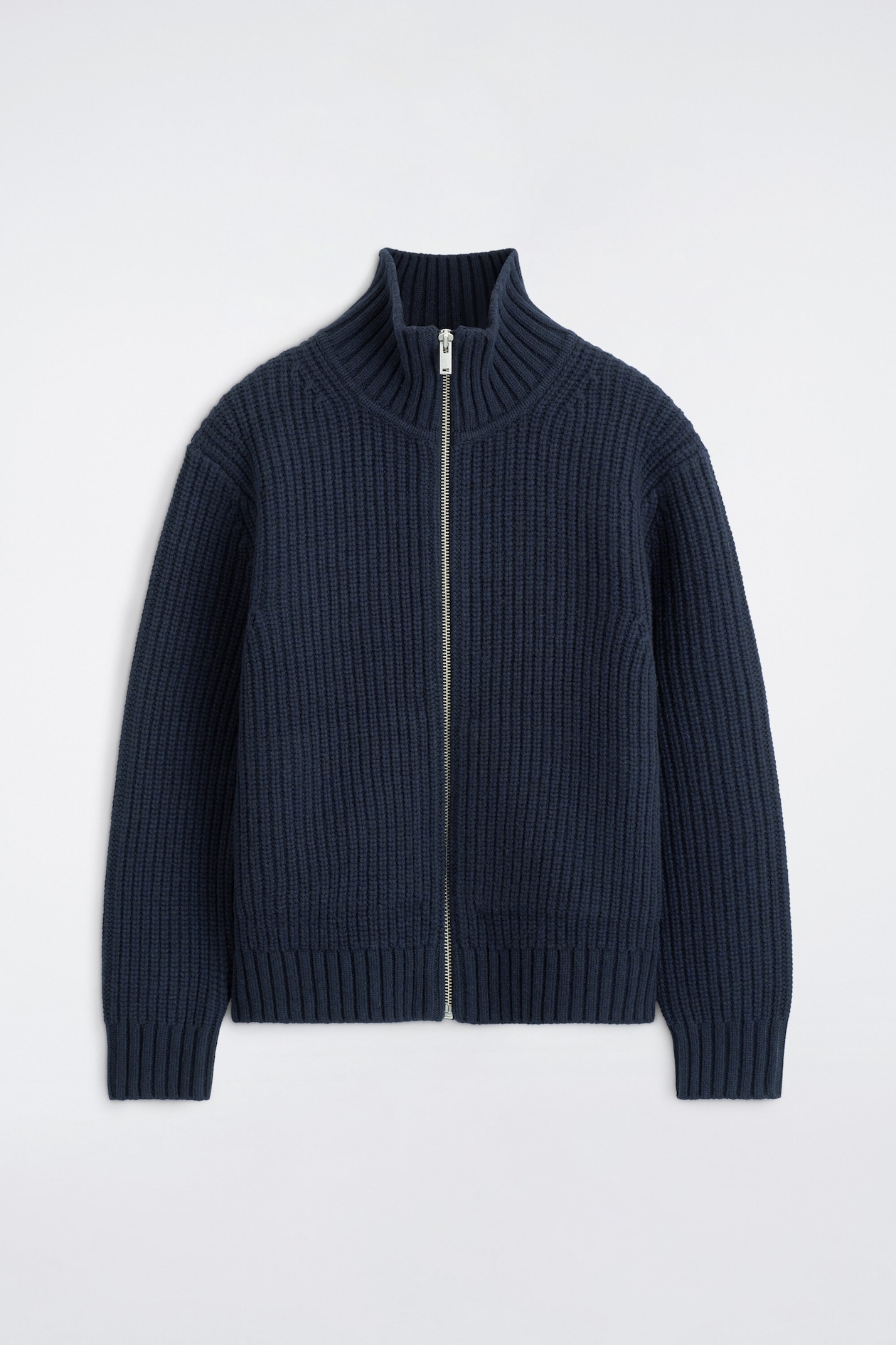 A navy blue ribbed-knit cardigan is shown from the front, featuring a high stand-up collar, a full-length silver-tone zipper, and ribbed trim on the cuffs and hem.