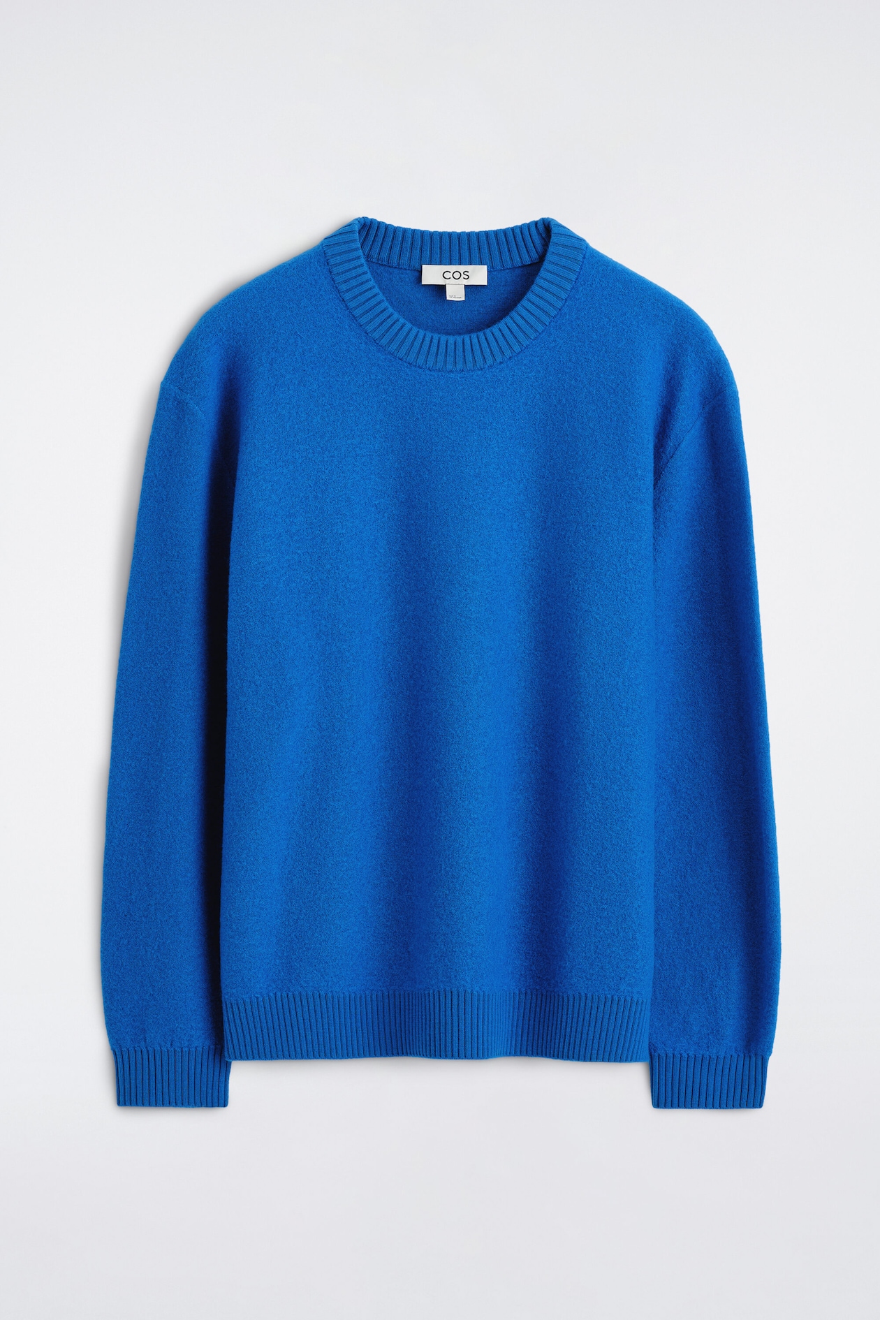 A boiled merino wool crew-neck sweater in vibrant blue is shown from the front, showcasing its soft, textured knit. The sweater features a thick ribbed neckline, ribbed cuffs, and a ribbed hem.