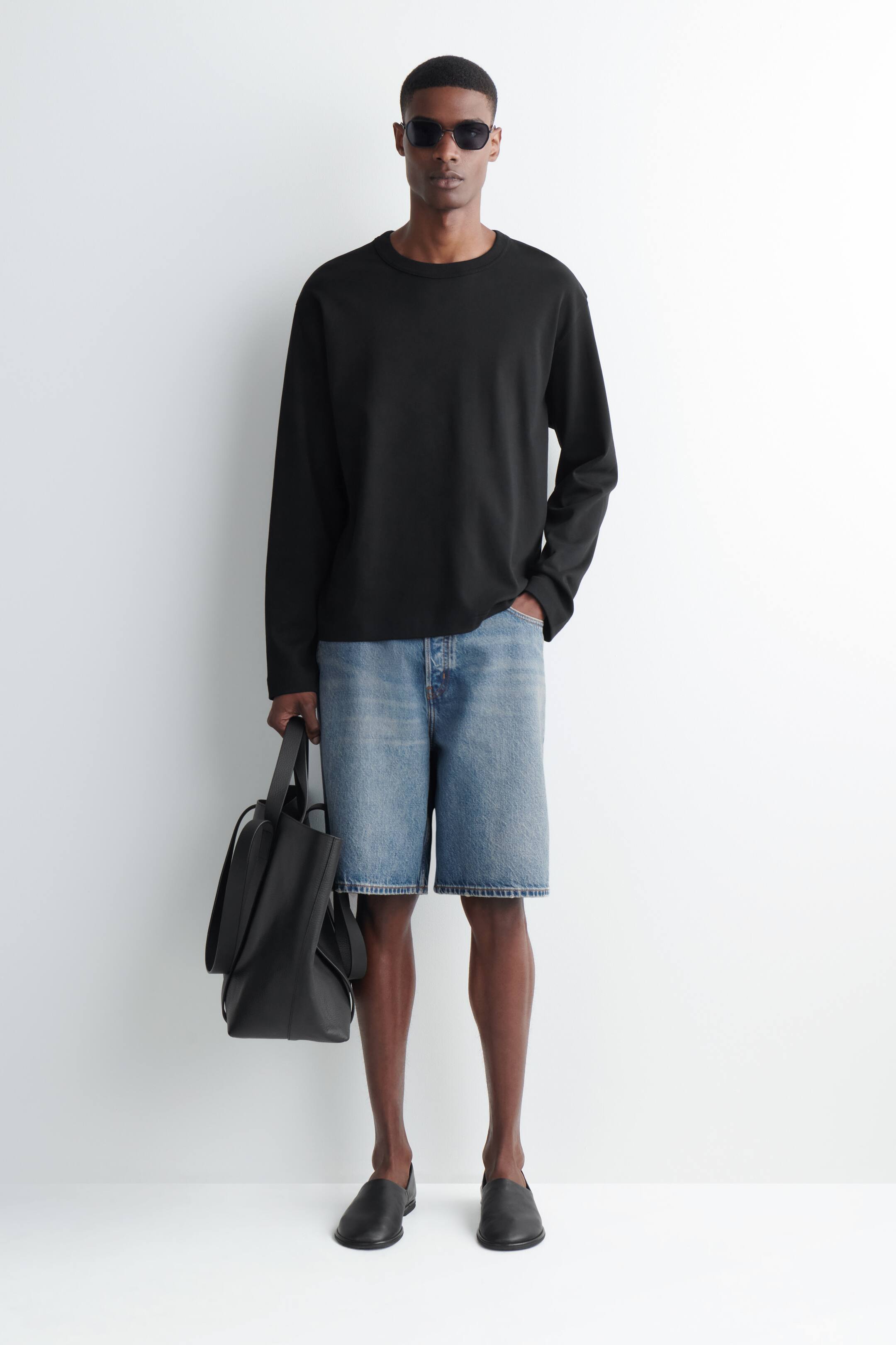 Ver imagen más grande: La modelo lleva puesto un top negro de manga larga con cuello redondo y ajuste holgado.