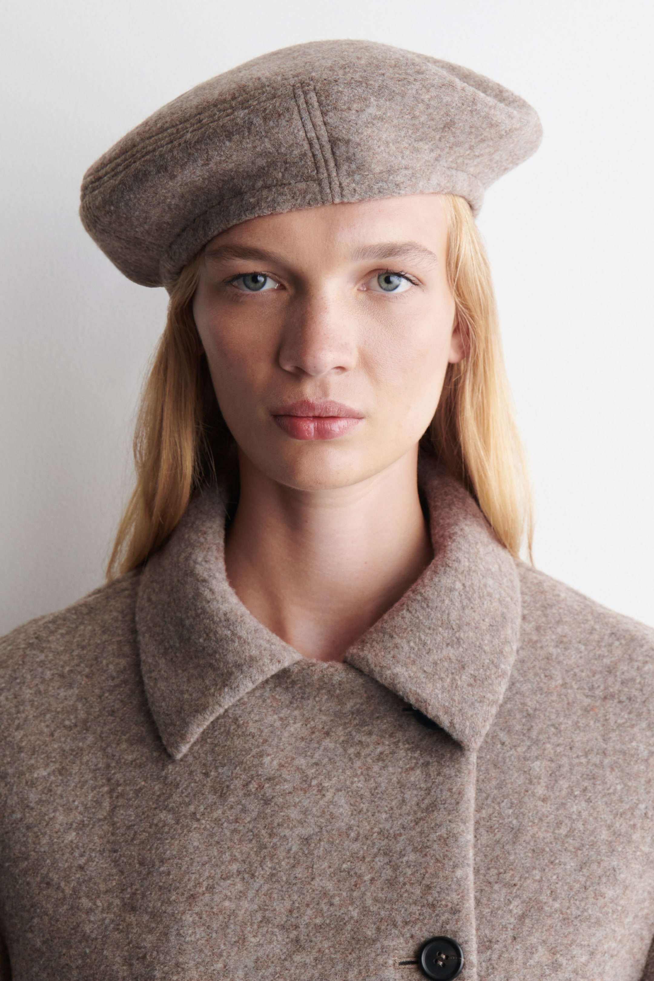Agrandir l'image: Un béret beige-mélangé est présenté de face, affichant une apparence douce et texturée avec des coutures visibles segmentant sa couronne arrondie.