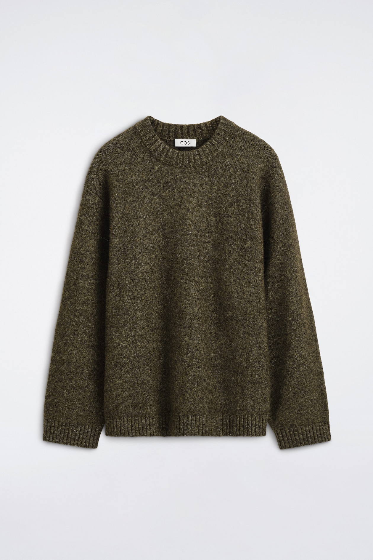 The oversized alpaca-blend crew-neck jumper is shown from the front, showcasing a textured, fuzzy olive-green mélange knit with dropped shoulders. The garment features a ribbed crew neck, ribbed cuffs, and a matching ribbed hem.